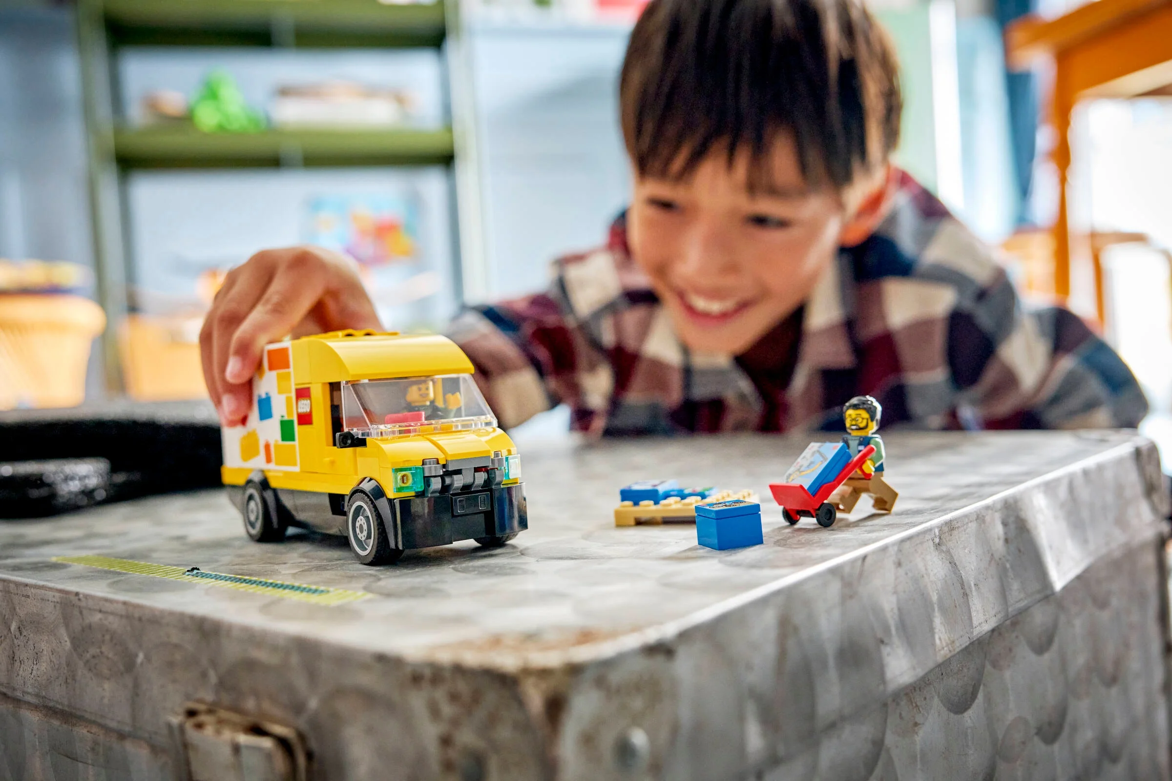 Copil zâmbitor se joacă cu furgoneta LEGO galbenă și minifigurine. Joacă creativă cu LEGO.