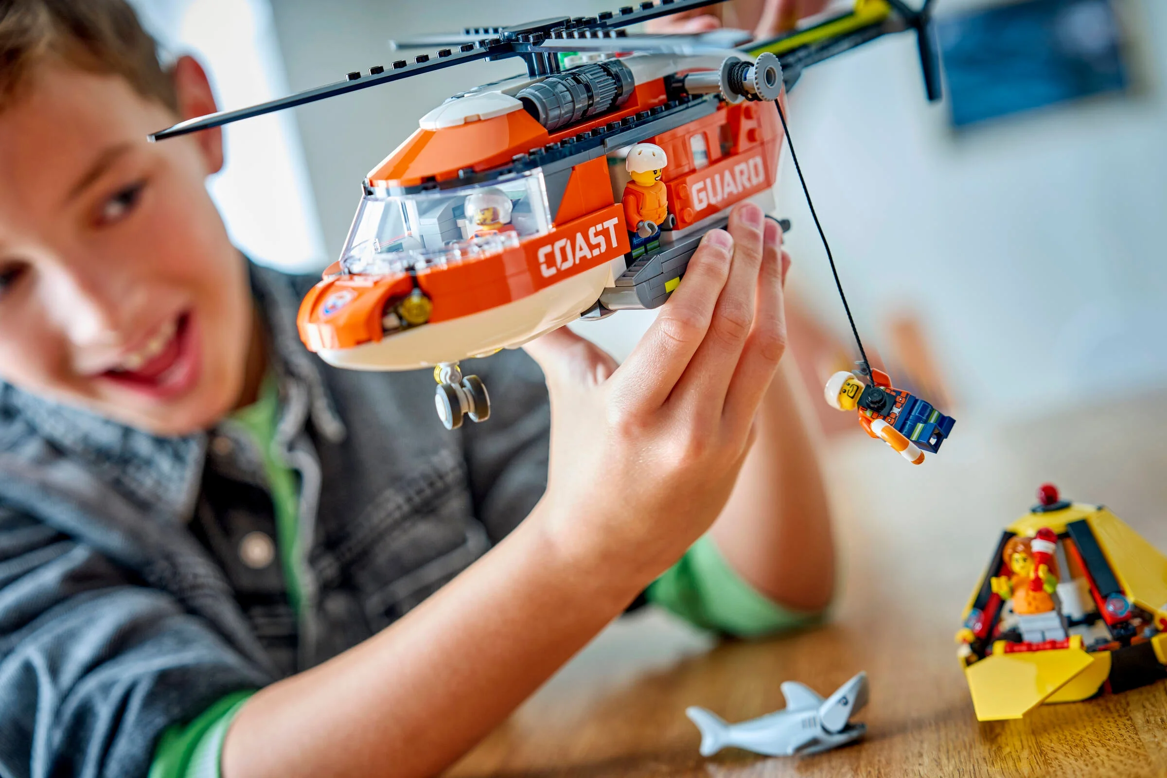 Un copil se joacă cu elicopterul de salvare LEGO City, scoțând o minifigurină pe targă.