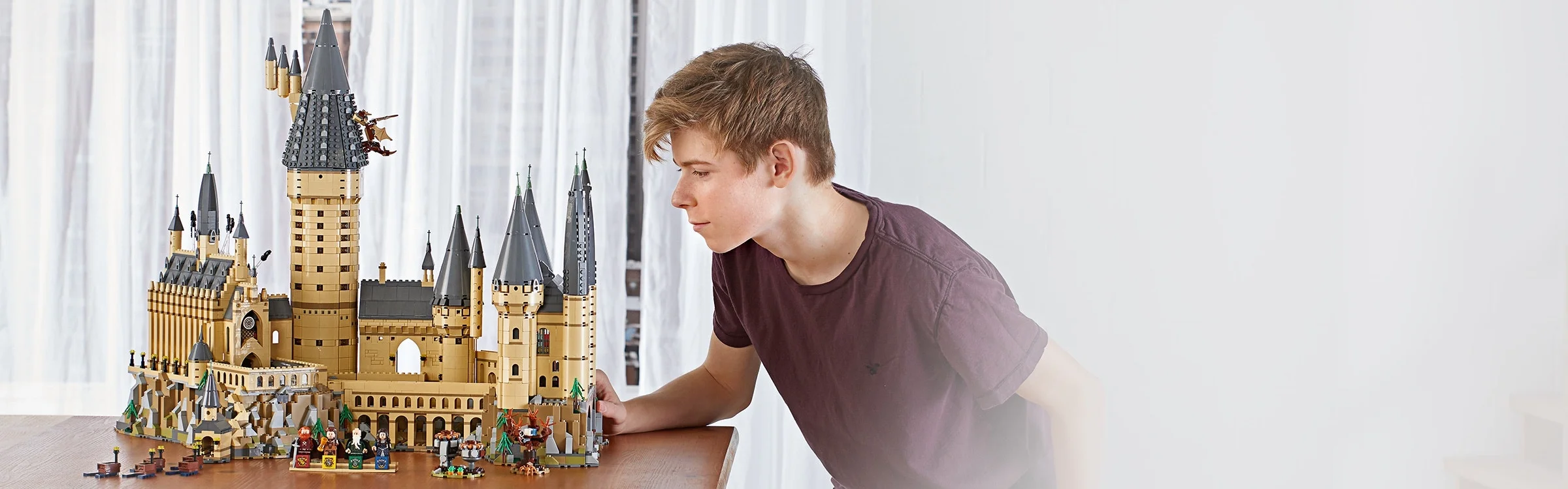 Modelul Hogwarts Castle (71043) expus, cu un adolescent privind construcția detaliată.
