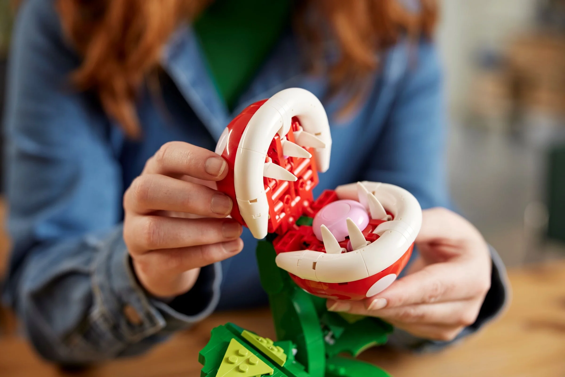 Femeie manevrând Piranha Plant LEGO, model detaliat și colorat.
