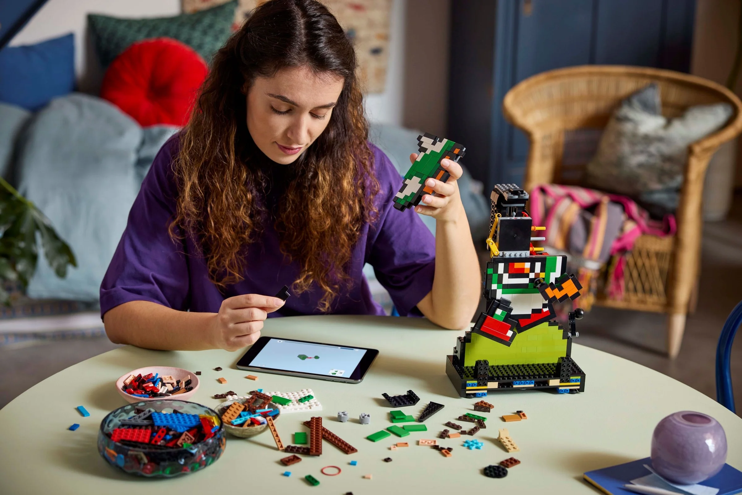 Femeie asamblând setul LEGO Mario & Yoshi, urmărind instrucțiuni pe tabletă.