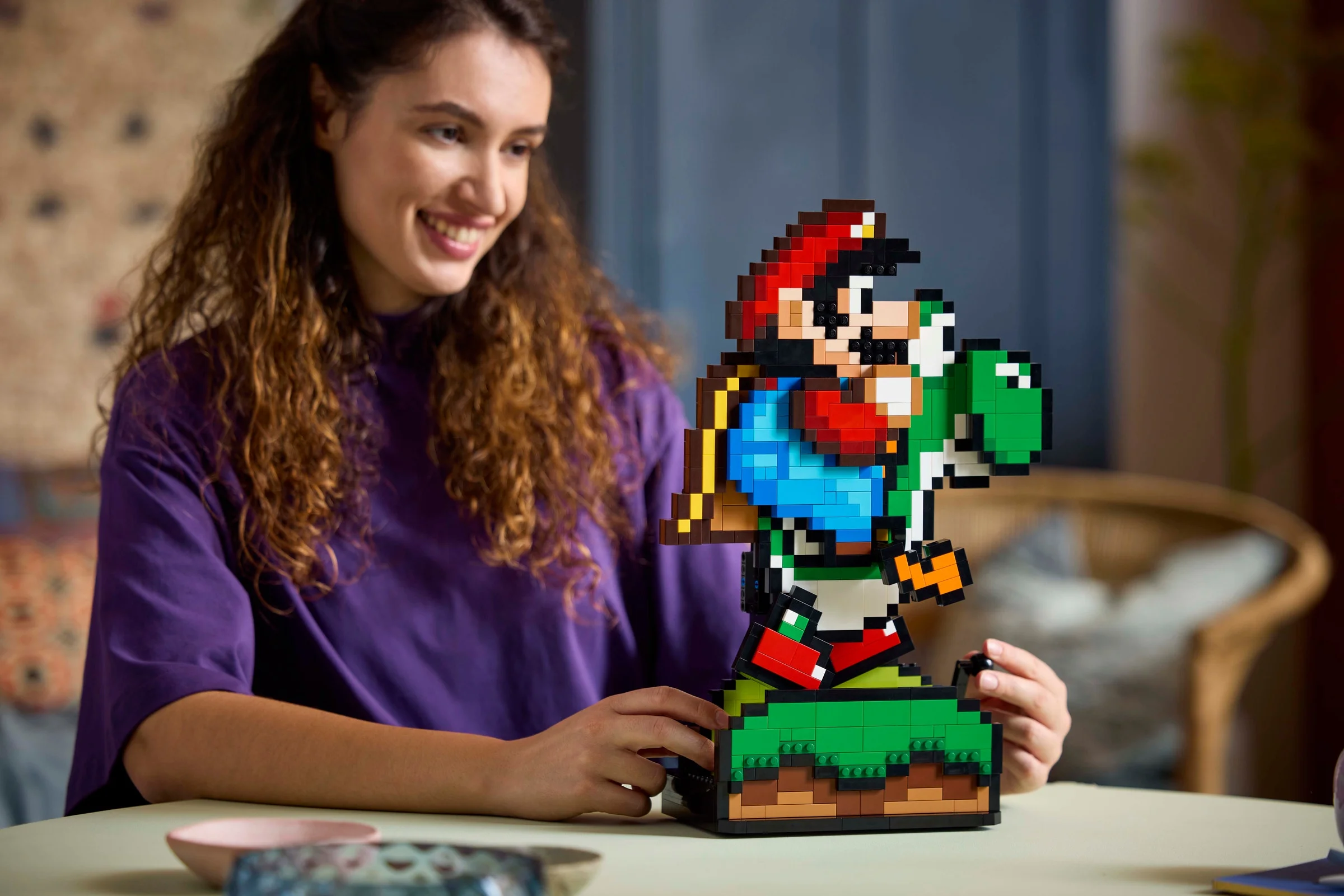 Mario și Yoshi construiți din cărămizi LEGO, prezentați de o tânără zâmbitoare.