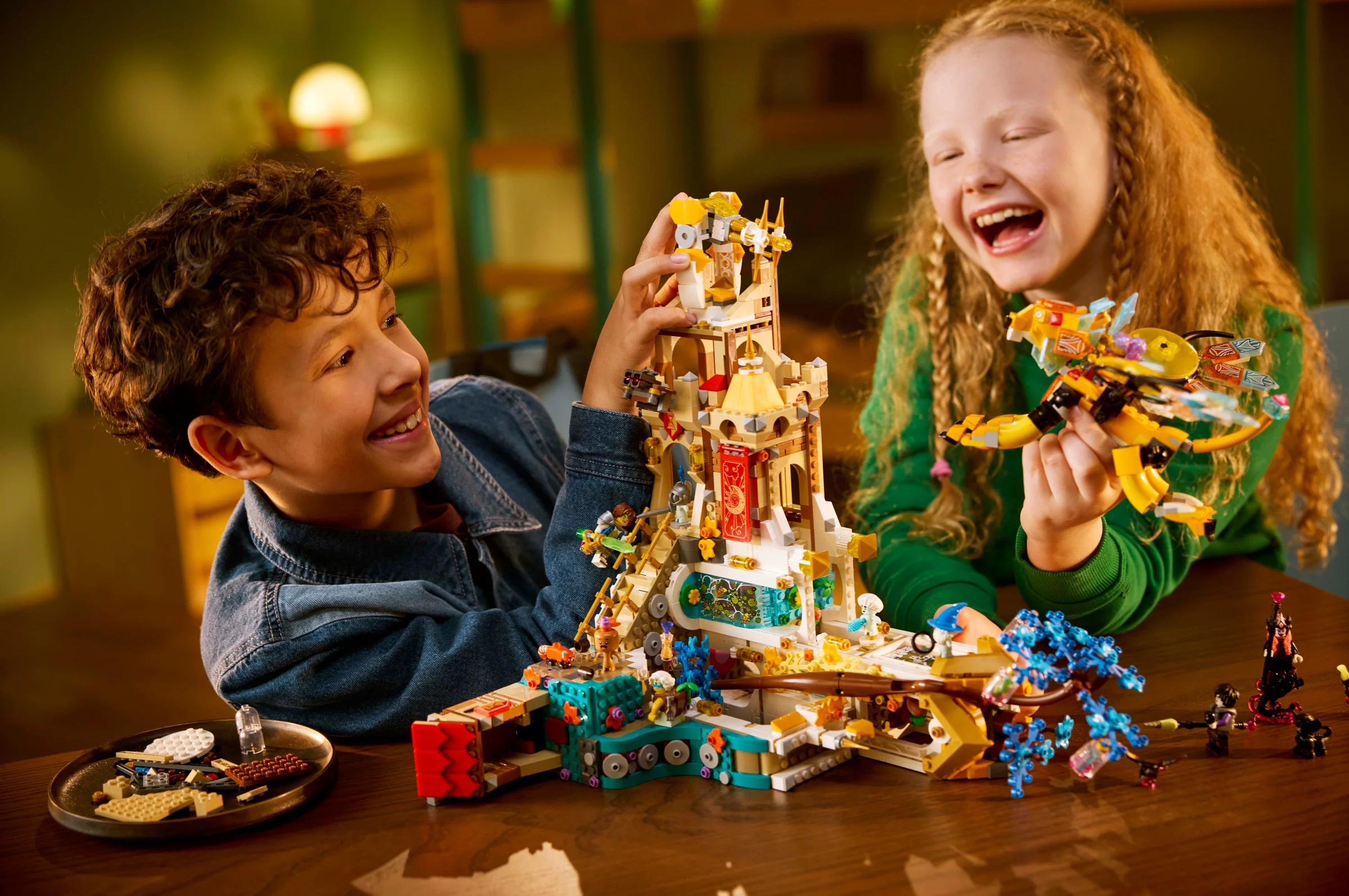 Copii zâmbitori se joacă cu setul LEGO DREAMZzz 71486 Castelul Nocturnia, modelul finalizat fiind în prim plan.