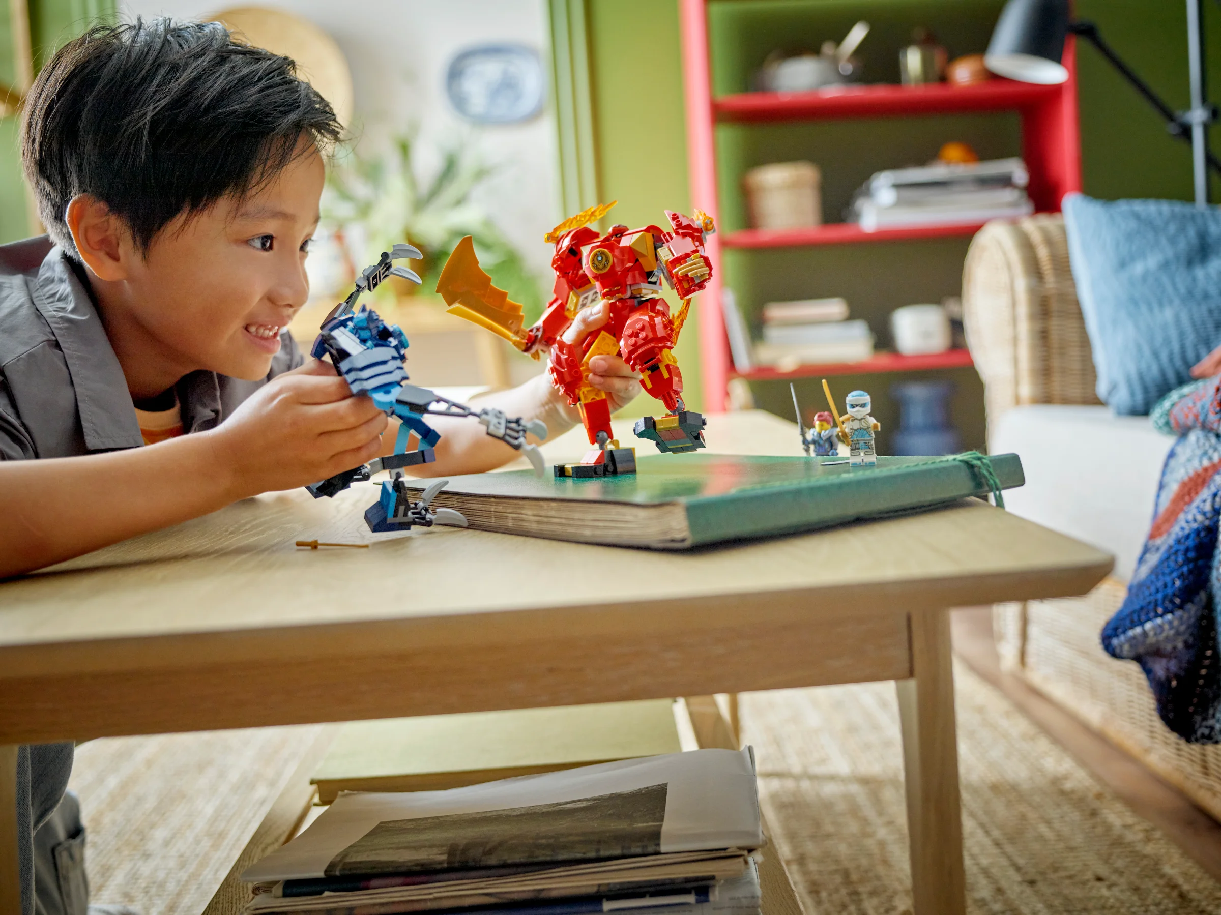 Băiat se joacă cu roboții LEGO Ninjago, simulând o luptă pe o carte.