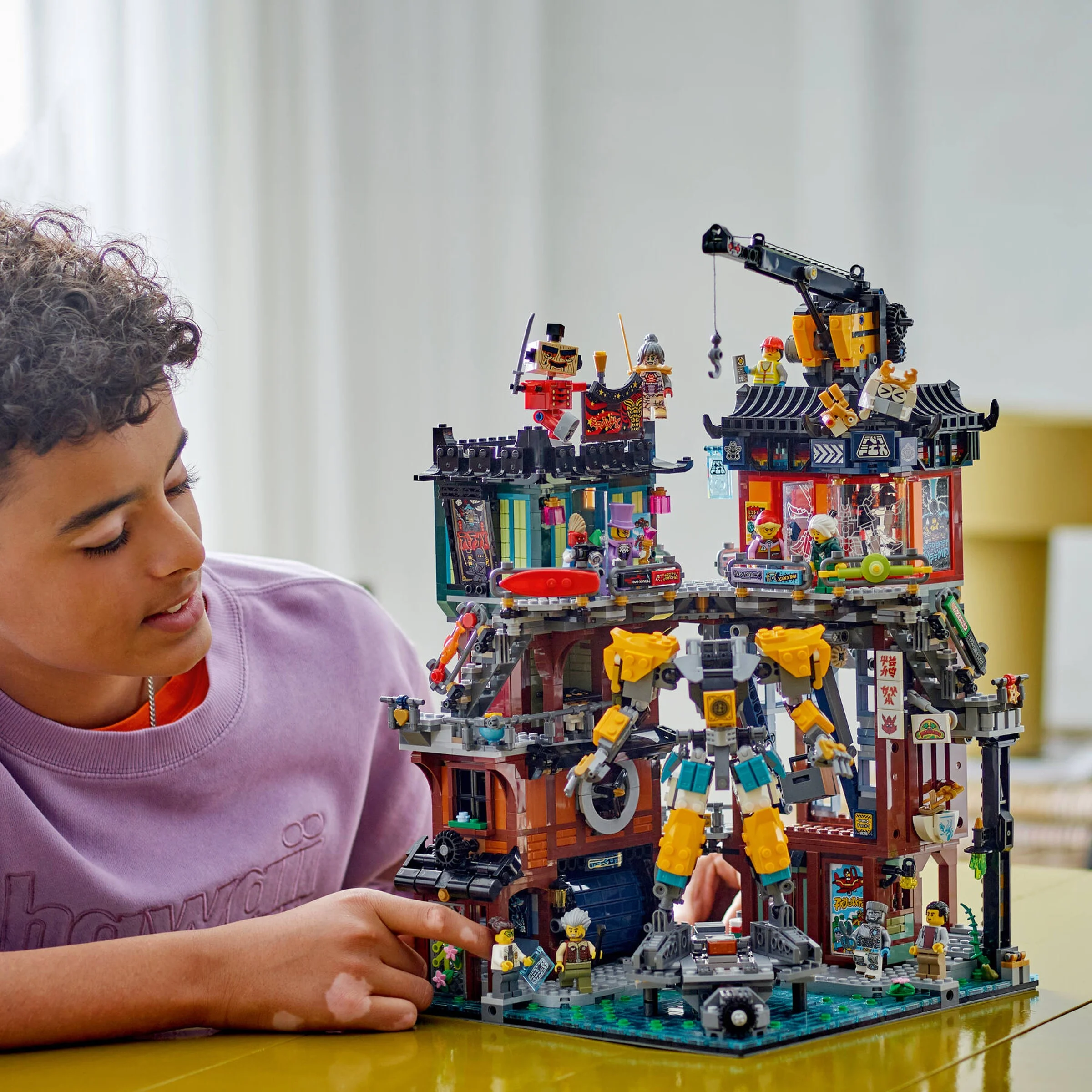Copil interacționând cu setul LEGO NINJAGO City Workshops. 