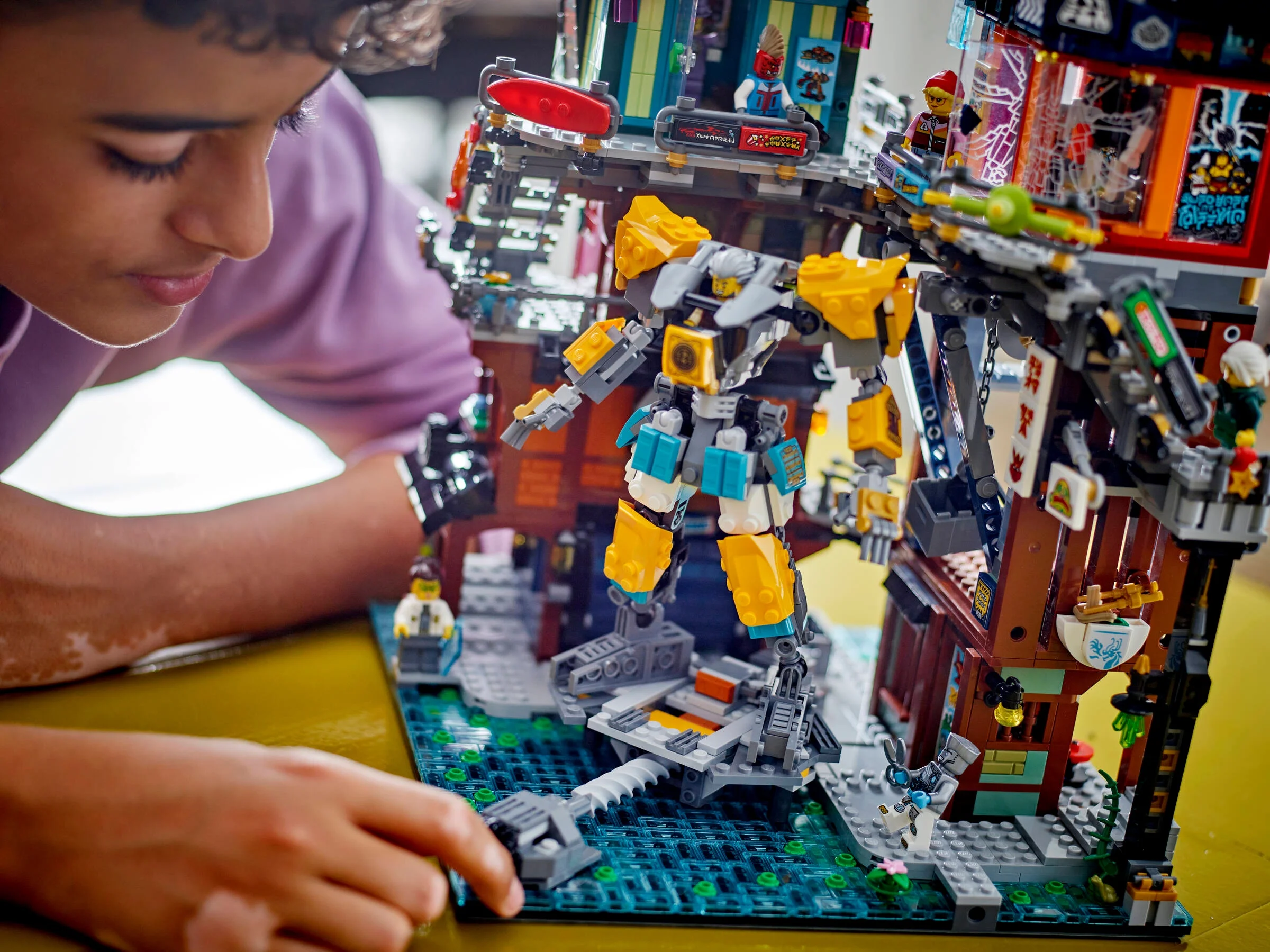 Un copil se joacă cu setul LEGO Ninjago 71837, atelierele din oraș.