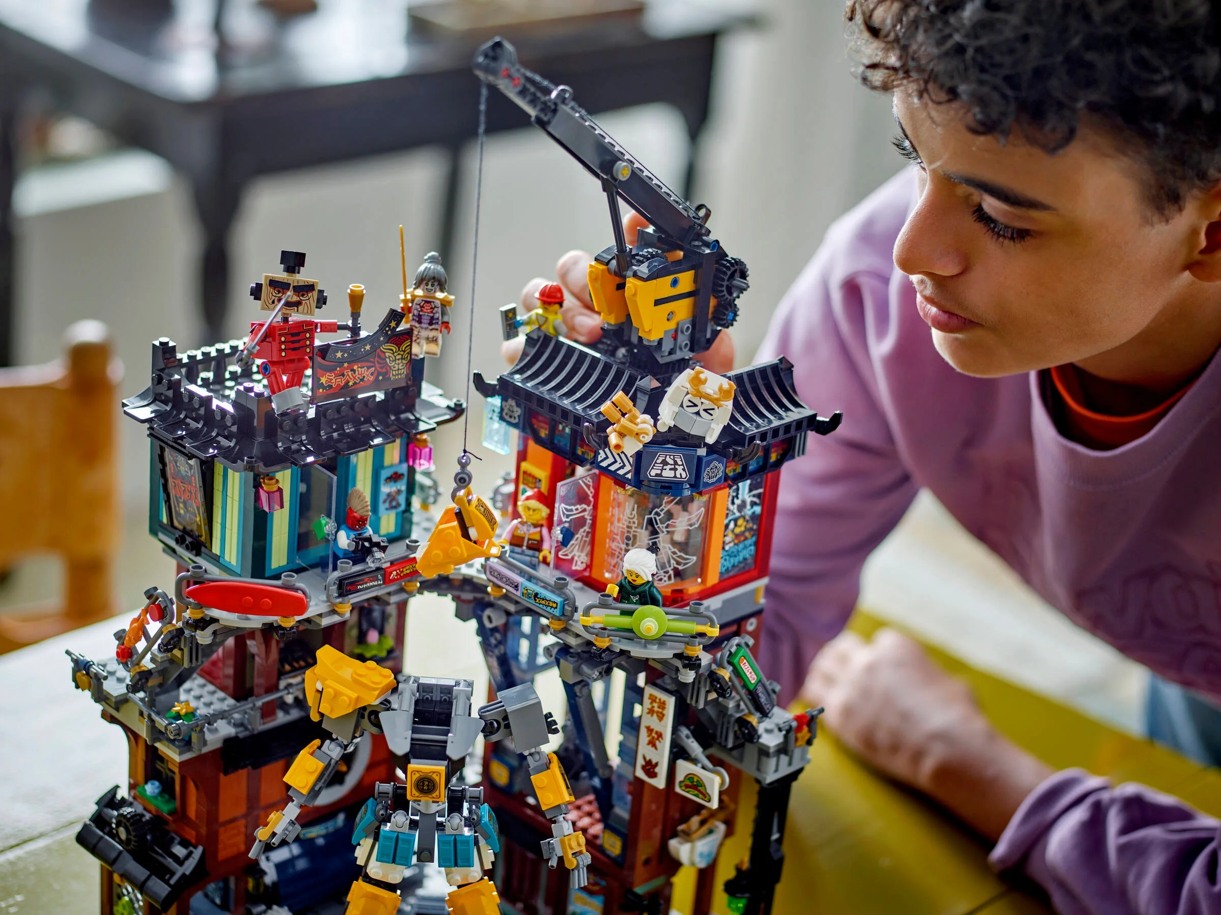 Un copil se joacă cu setul LEGO Ninjago City Workshops. Atmosferă captivantă.