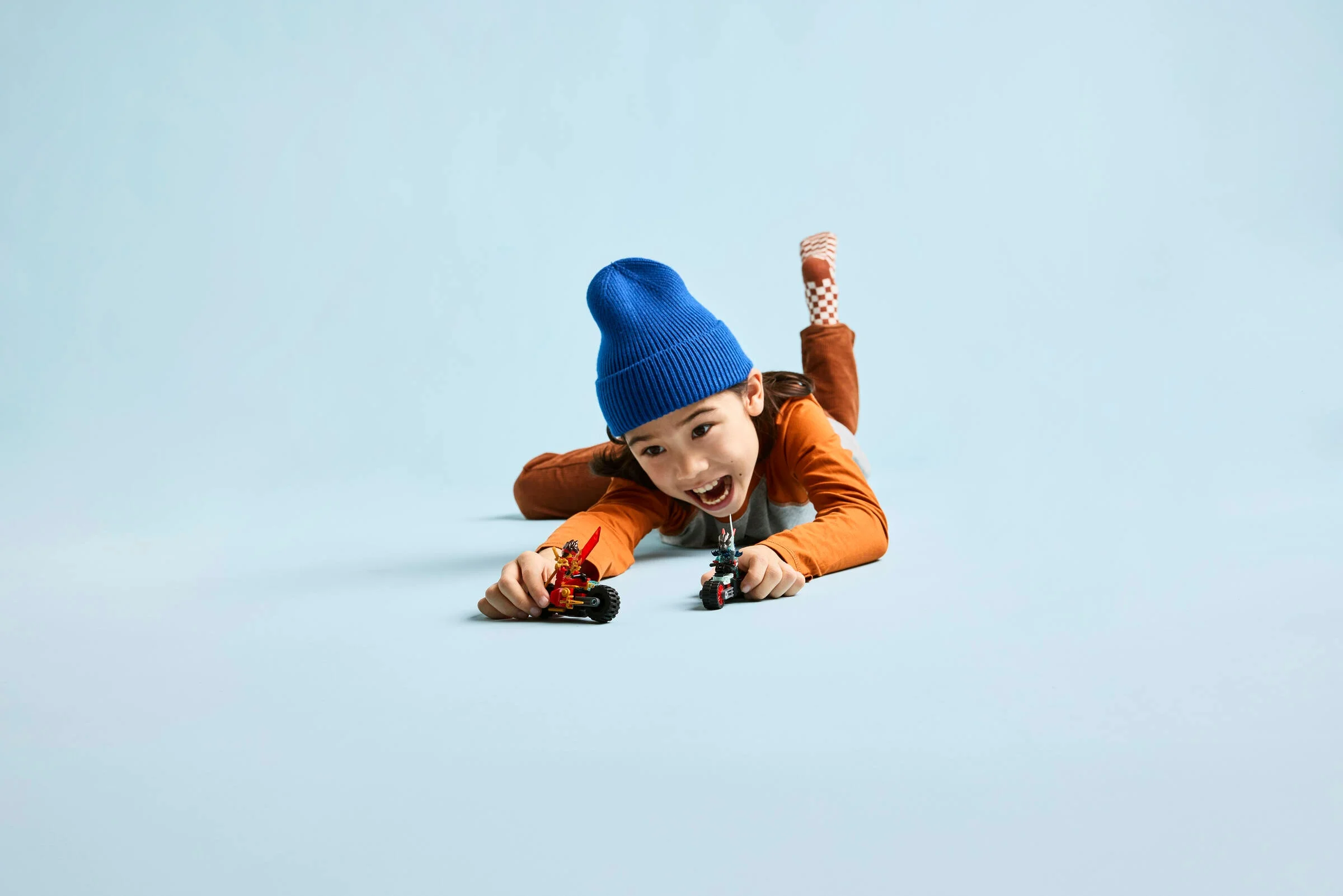 Copil jucându-se cu motocicletele LEGO Ninjago, imagine dinamică.