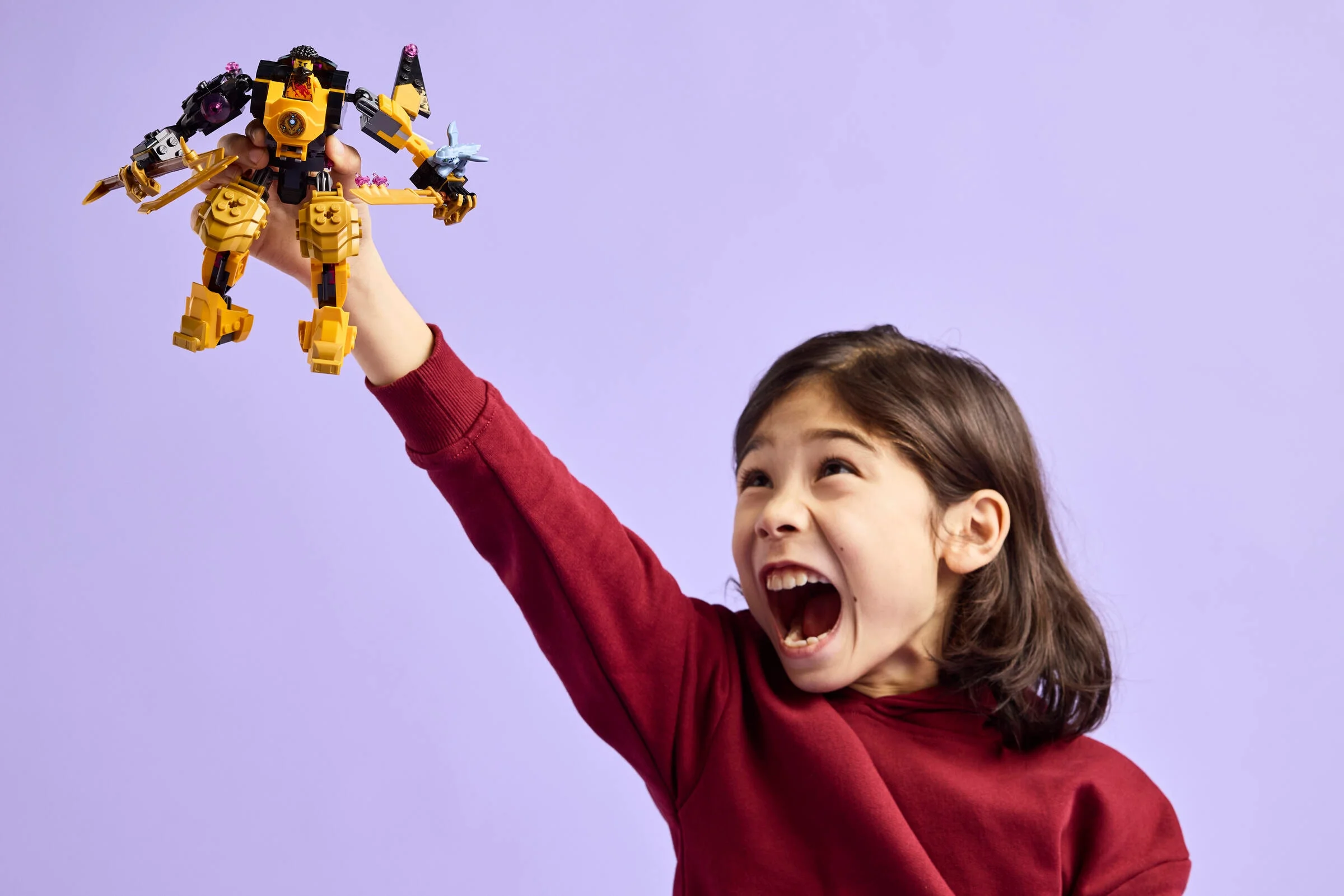 O fetiță entuziasmată ridică robotul LEGO Arin. Joacă și aventură Ninjago.