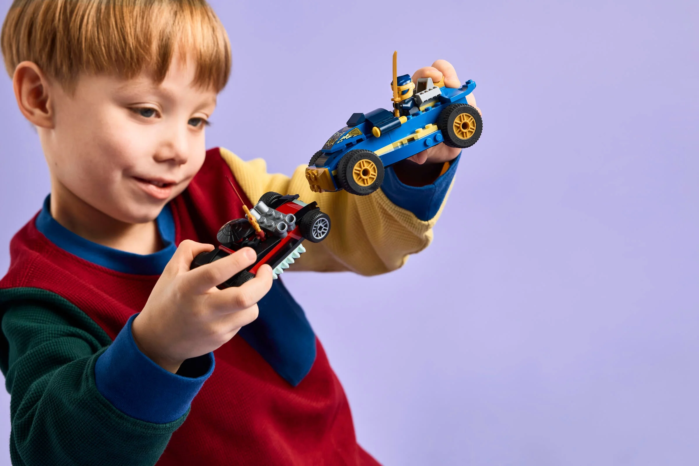 Un copil ține în mâini mașinile de curse Lego Ninjago Rogue vs. Drix. Joacă-te cu setul!