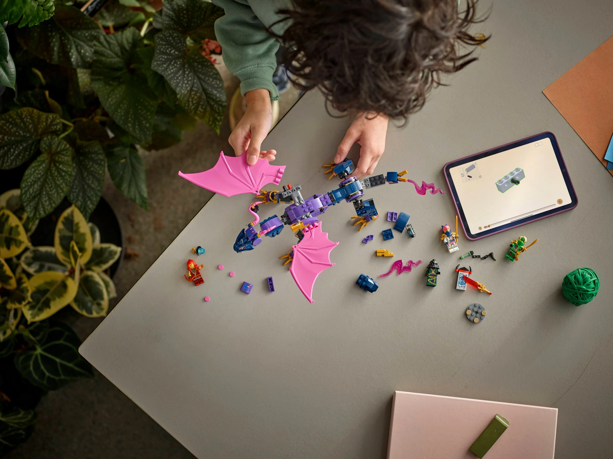 Copil construind Rontu, dragonul Ninjago 71842, urmând instrucțiunile de pe tabletă.
