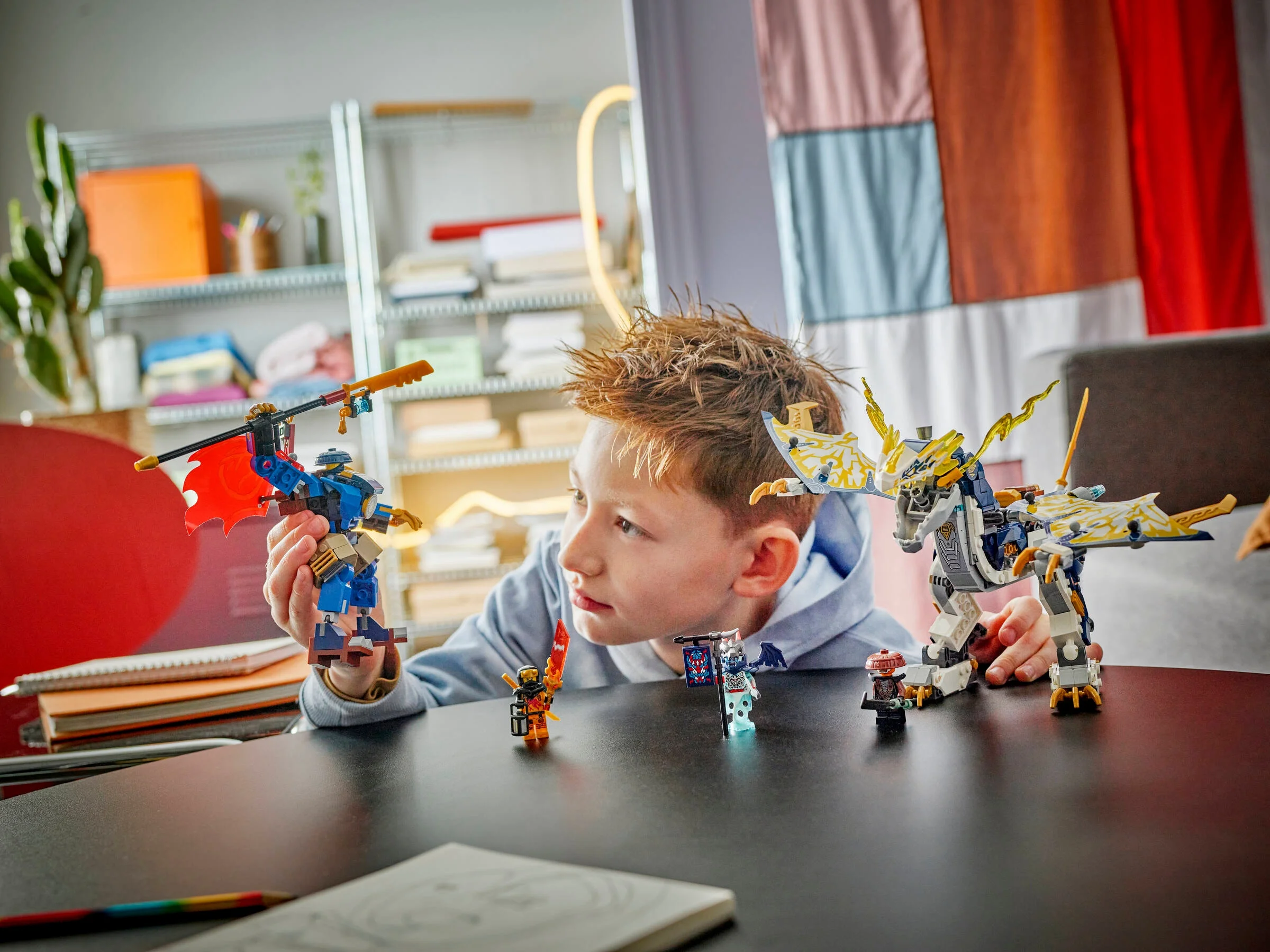 Imagine cu un copil jucându-se cu setul LEGO Ninjago 71843. Dragonul și mini-figurinele sunt vizibile.