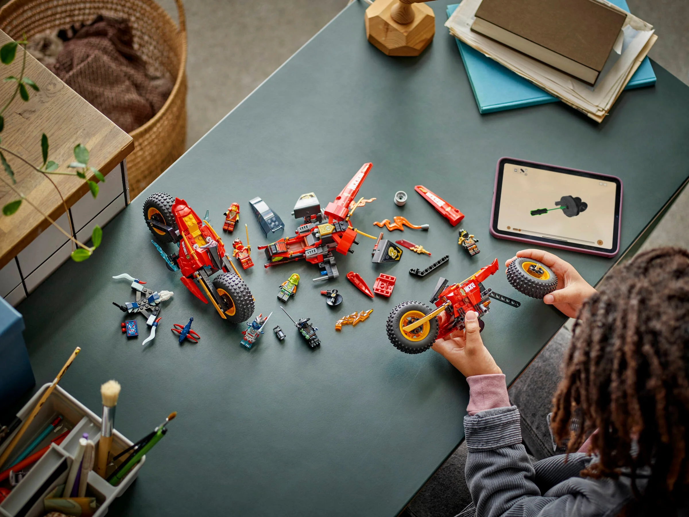 Copil construind vehiculul Ninja Combat cu instrucțiuni digitale pe tabletă. Set LEGO 71844.