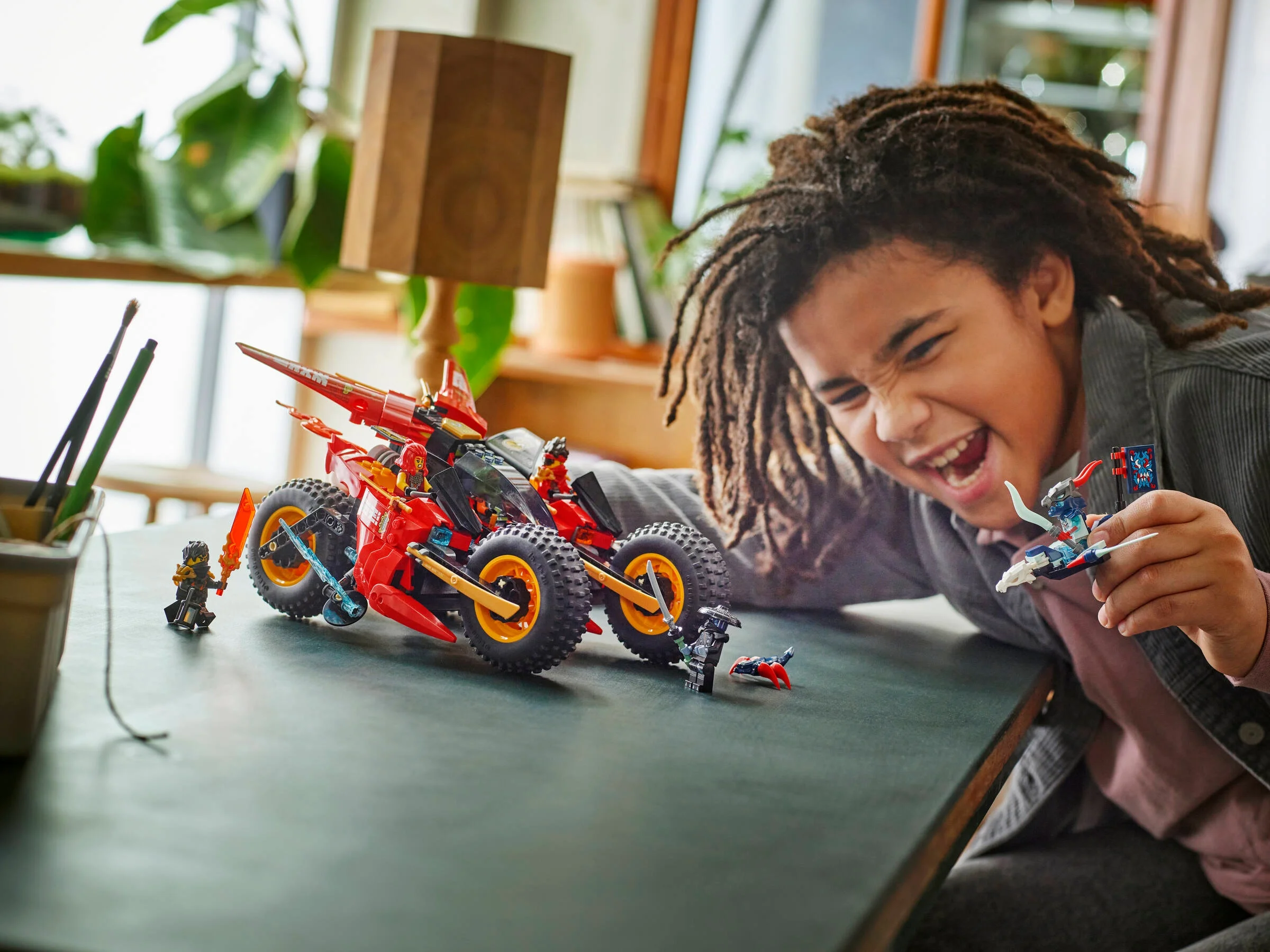 Copil entuziasmat jucându-se cu vehiculul de luptă ninja LEGO® Ninjago 71844.