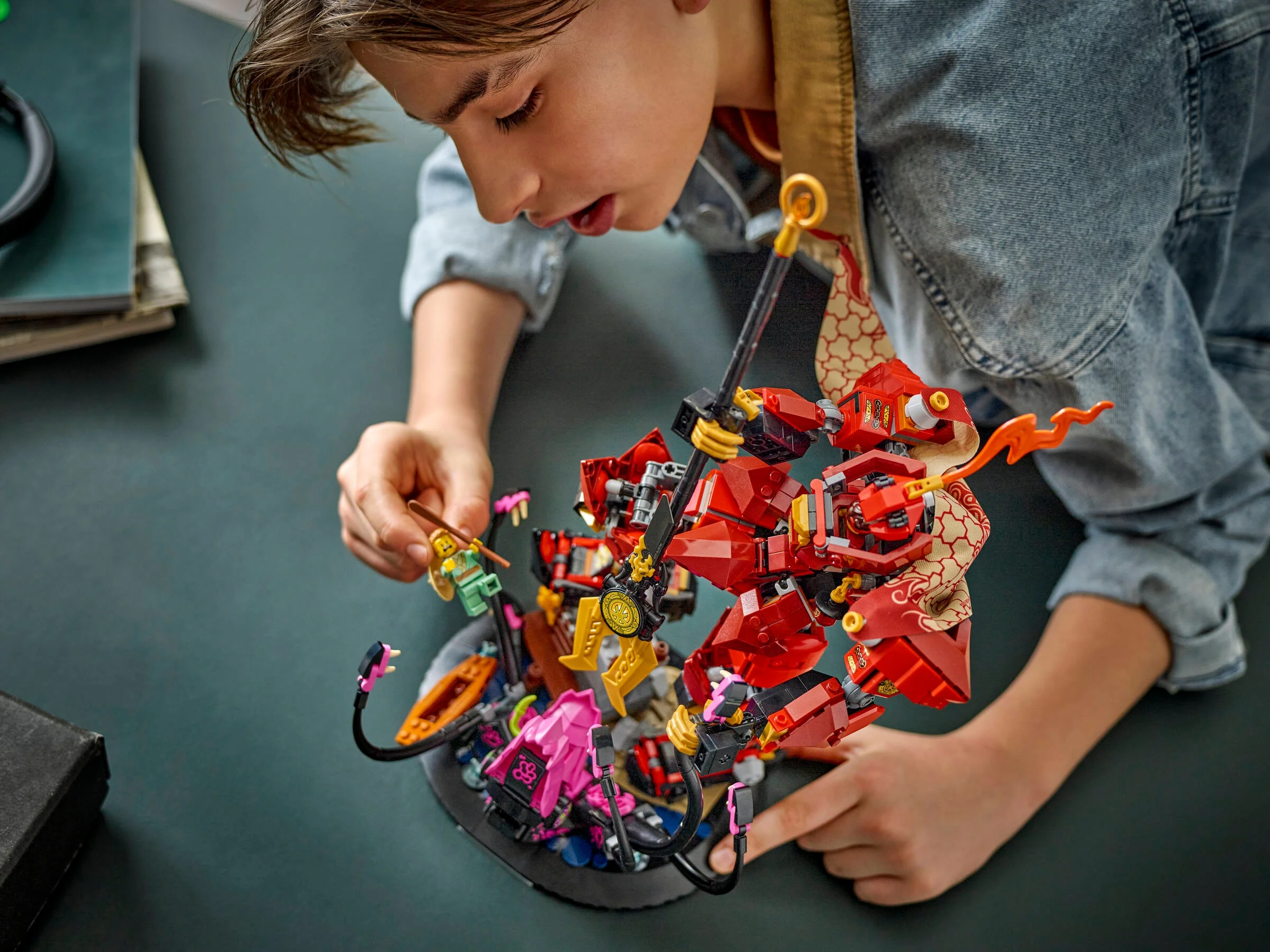 Băiatul se joacă cu robotul de foc Ninjago, explorând detaliile și aventurile posibile.