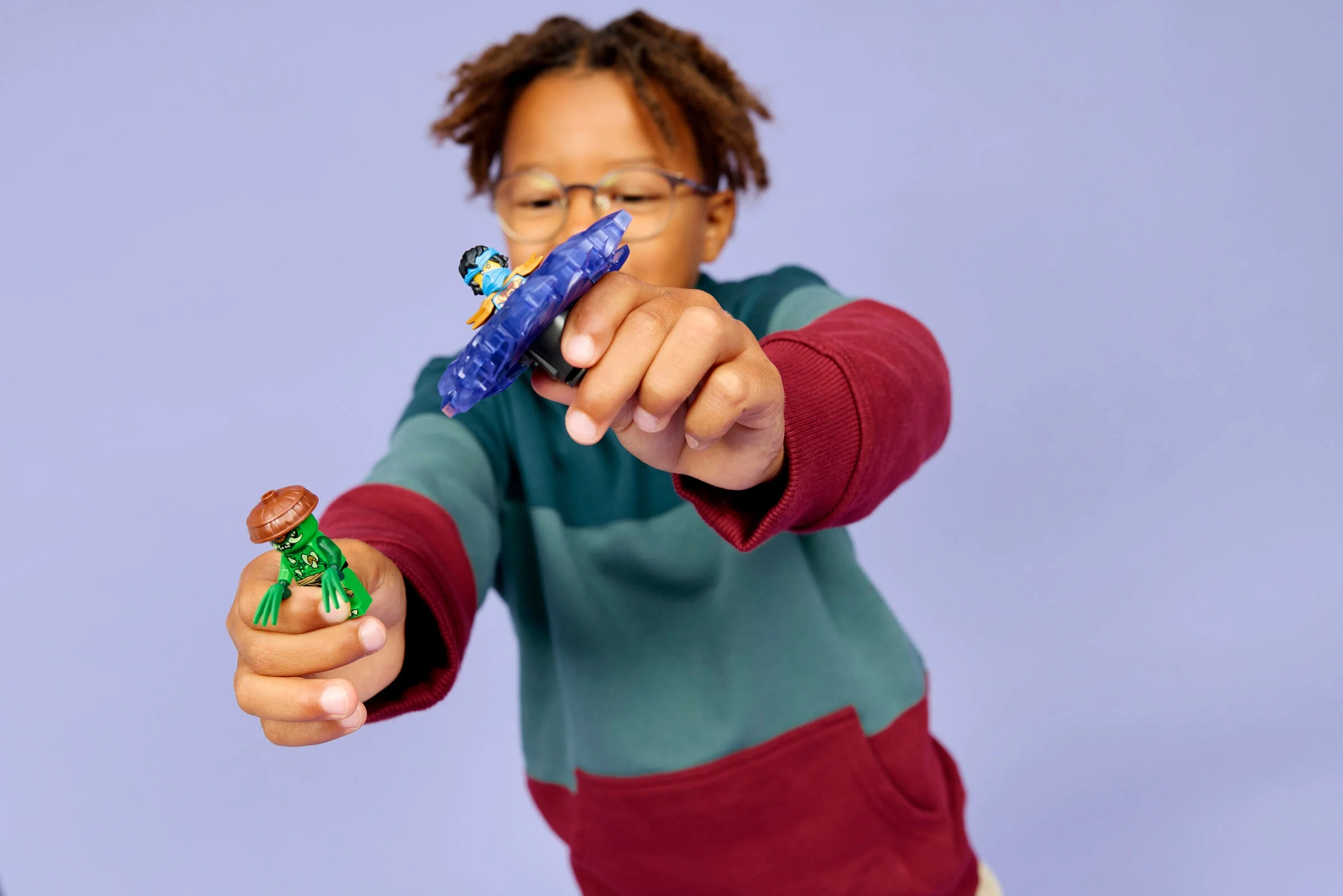Copil se joacă cu minifigurinele Nya și monstru mutant LEGO, arătând funcția spinner.