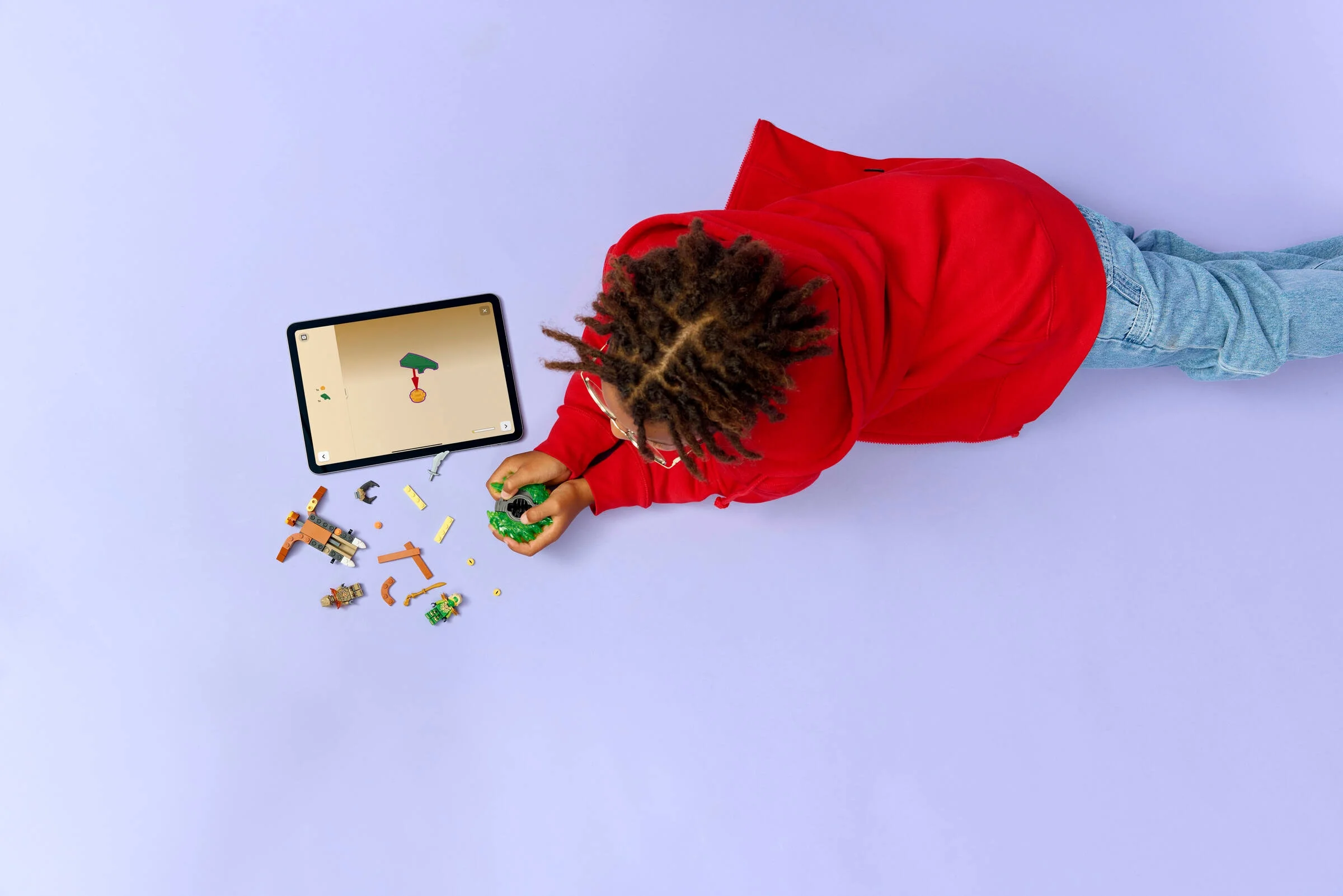 Copil construind setul LEGO Ninjago 71850. Instrucțiuni pe tabletă, piese împrăștiate.