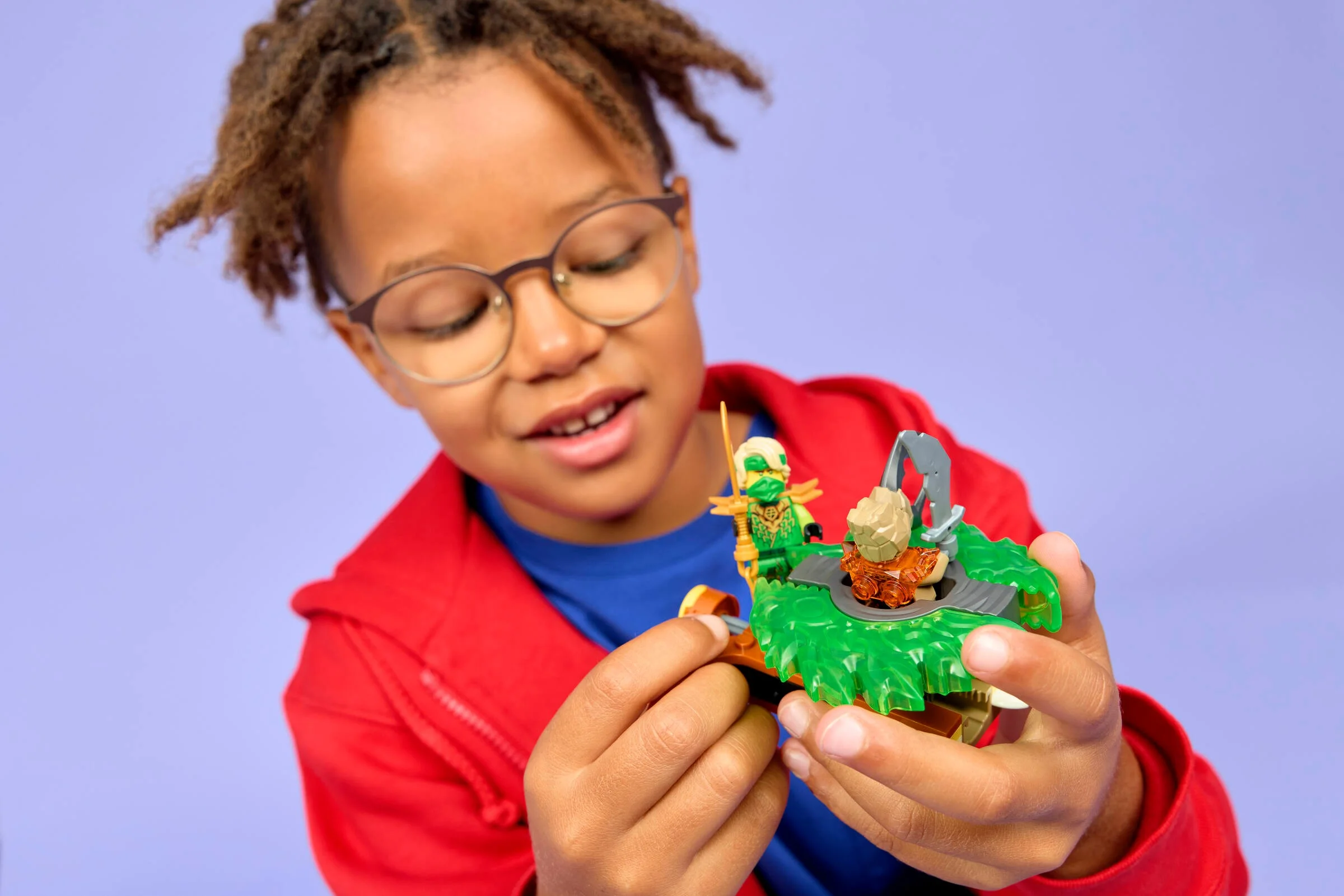 Copil se joacă cu setul LEGO Ninjago 71850, spinner-ul Lloyd vs. Monstrul Pământului.