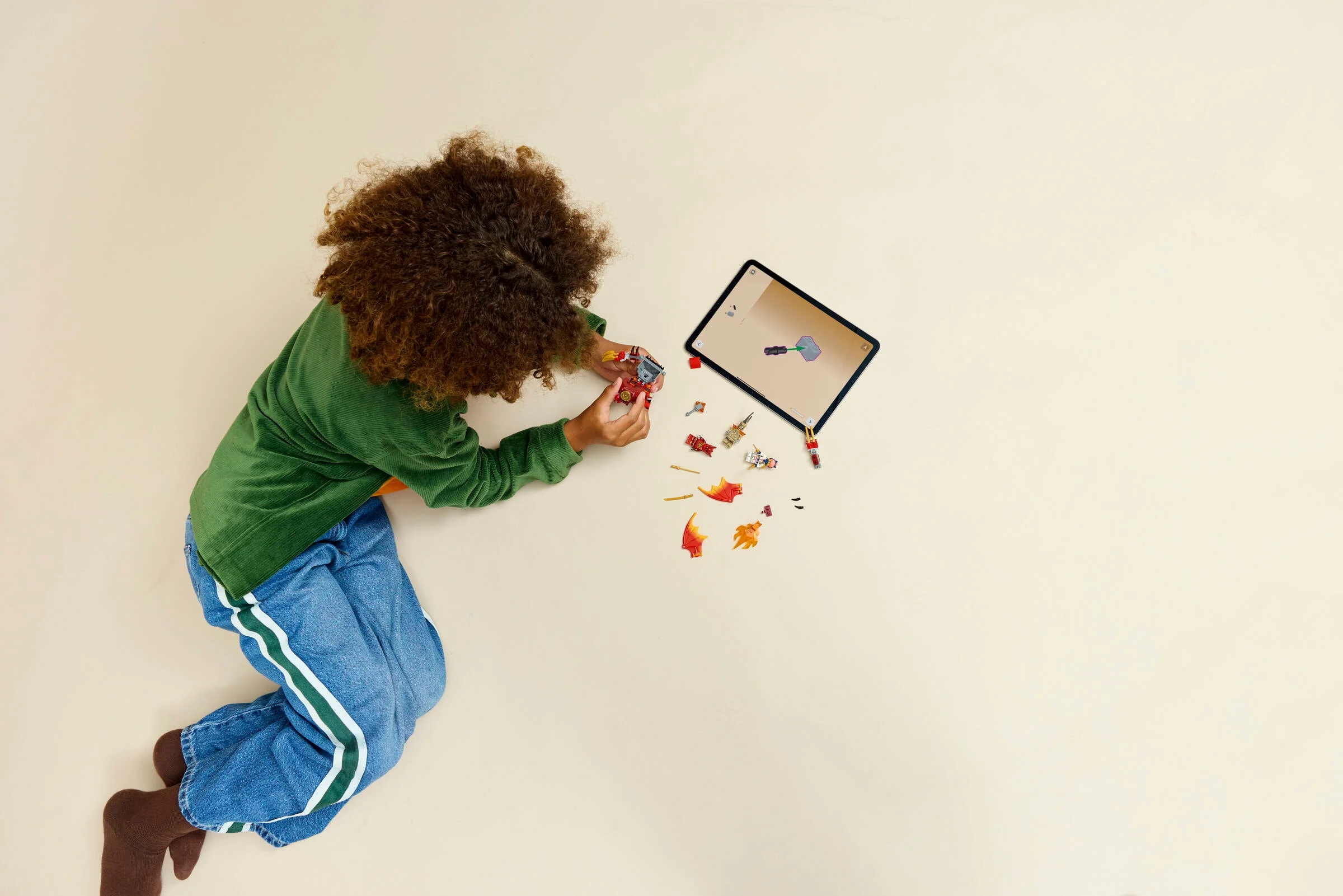 Copil construind setul LEGO Ninjago 71851, urmărind instrucțiunile pe tabletă.