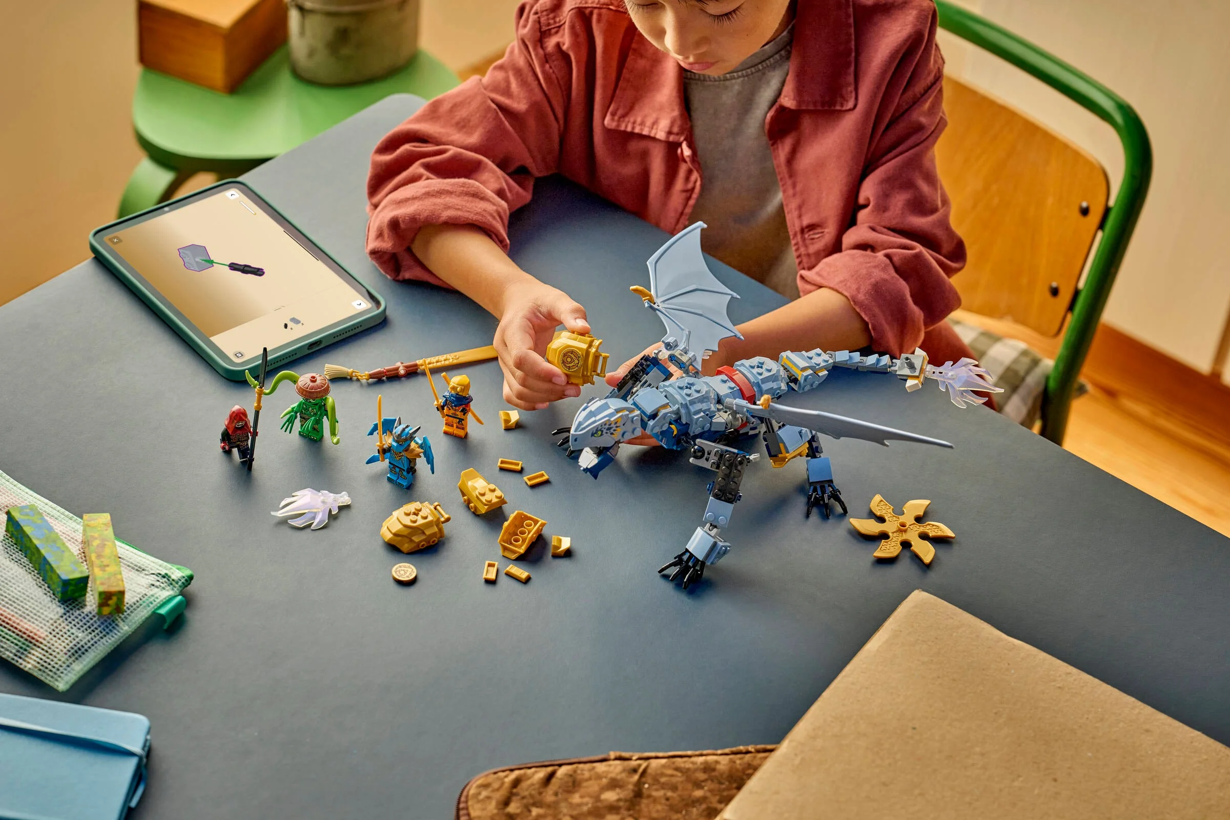 Copil construind dragonul Riyu Ninjago, folosind instrucțiuni digitale pe tabletă.