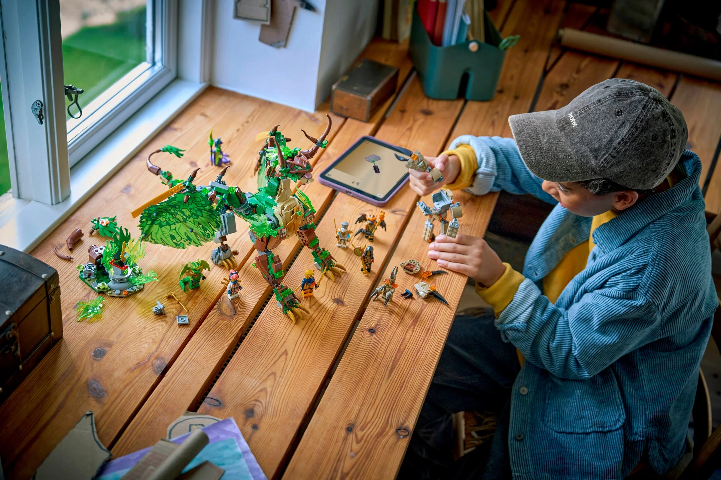 Un copil construiește setul LEGO Ninjago 71859, Dragonul Vieții, pe o masă de lemn lângă fereastră.