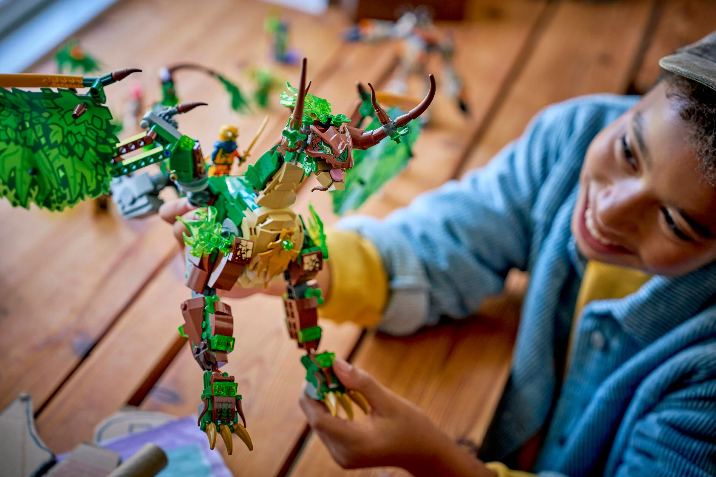 Un copil zâmbitor ține dragonul de viață LEGO® Ninjago 71859.