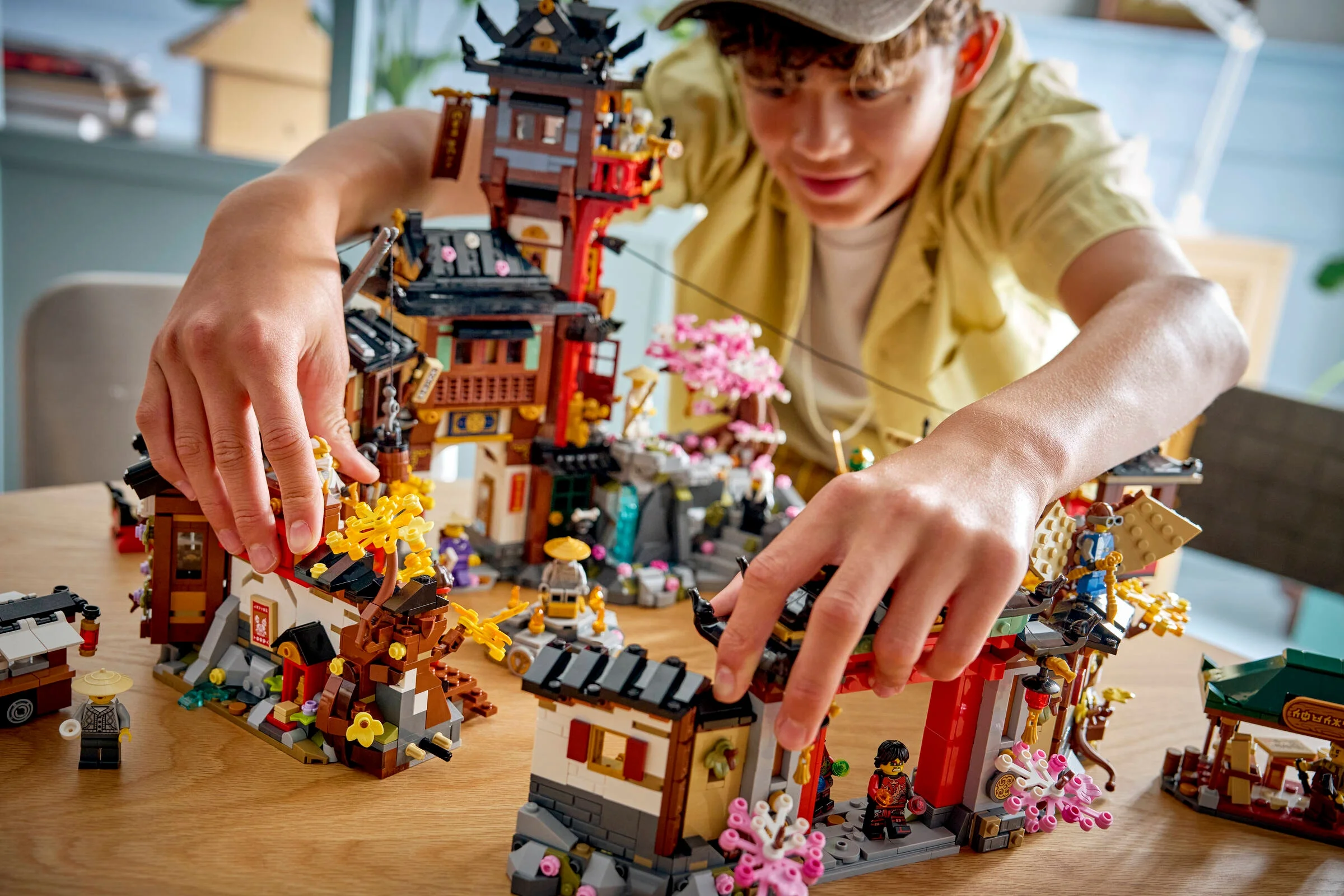 Copil construind setul LEGO Ninjago 71861 Orașul Vechi. Imagine detaliată cu modelul și minifigurinele.