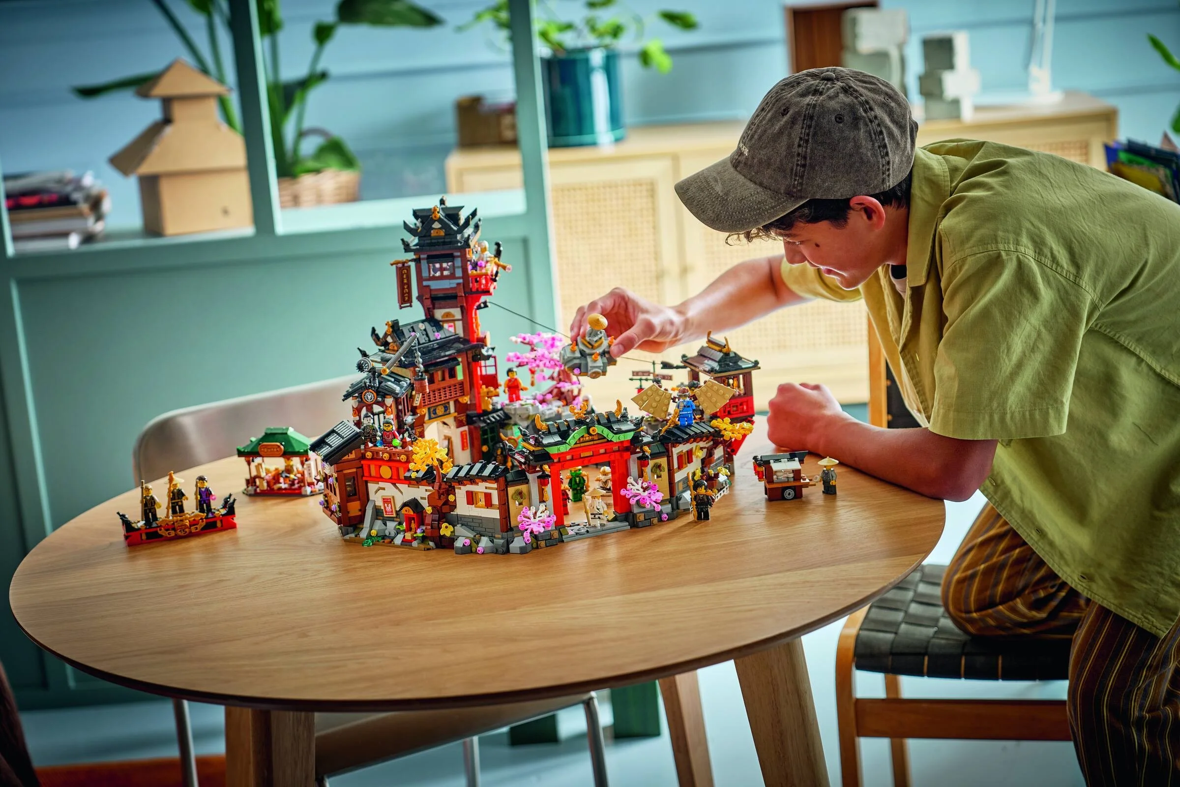 Imagine cu modelul LEGO Ninjago 71861 Vechiul Oraș, prezentat într-un cadru lifestyle, cu o persoană interacționând cu acesta.