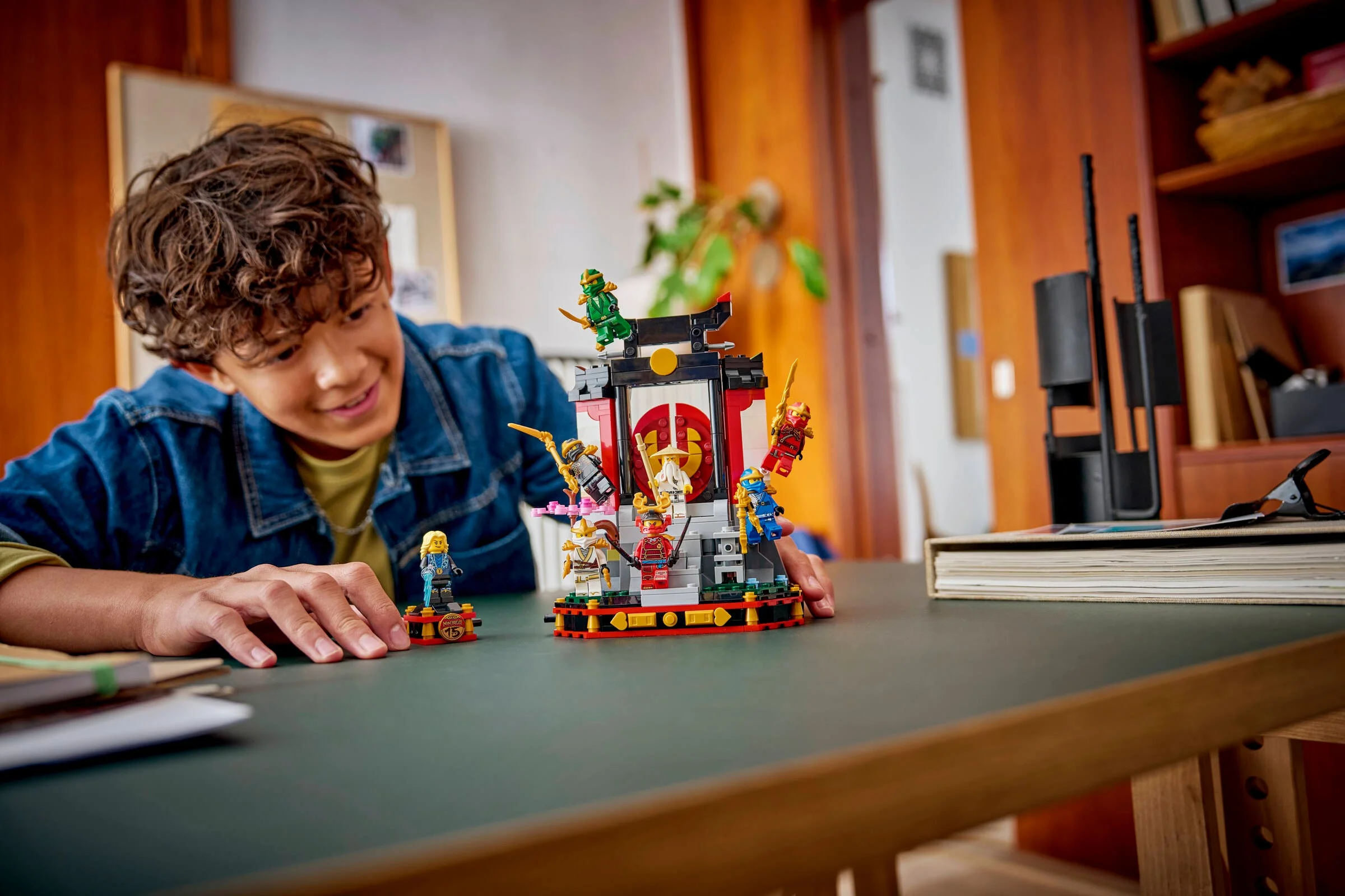 Copil interacționând cu setul LEGO Ninjago 71866, prezentând personajele ninja pe un suport.