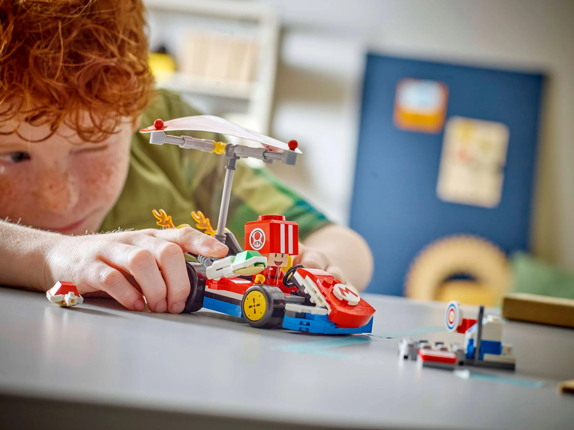 Copil construind kartul LEGO Super Mario. Detalii colorate și distractive.