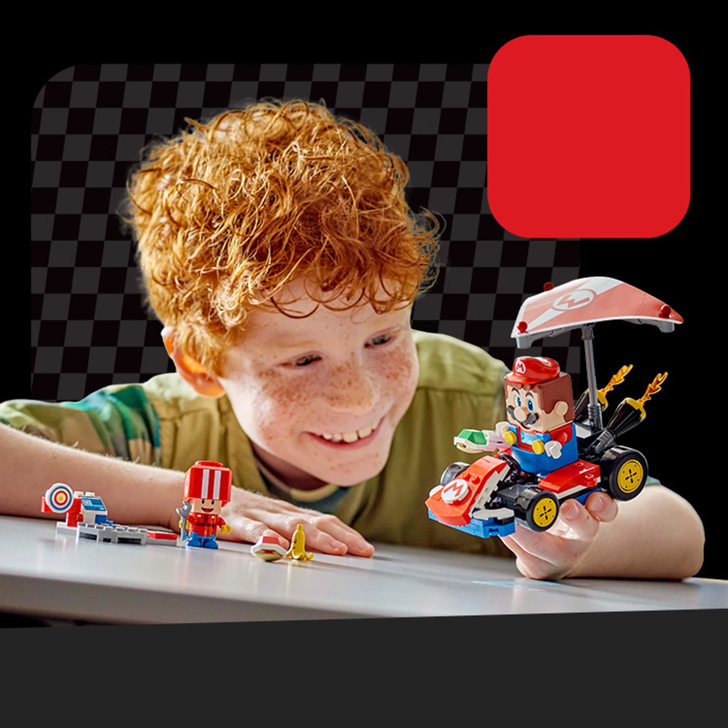 Băiat se joacă cu setul LEGO Mario Kart, zâmbind cu entuziasm.
