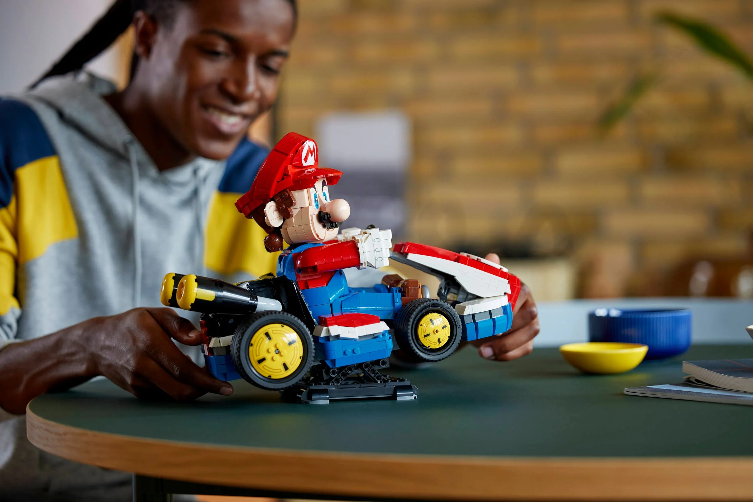 Bărbat zâmbitor ține setul LEGO Mario Kart, Mario și kartul standard.