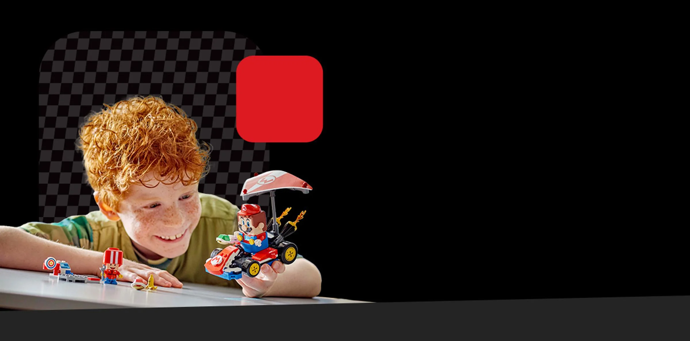 Un copil zâmbește și se joacă cu Mario în kartul său LEGO. O scenă distractivă cu setul LEGO Super Mario.