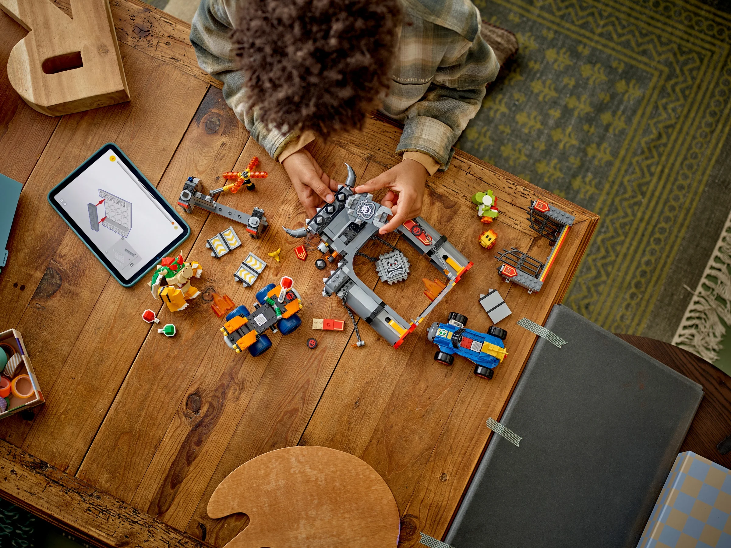 Copil construind Castelul lui Bowser LEGO, urmând instrucțiunile de pe tabletă.