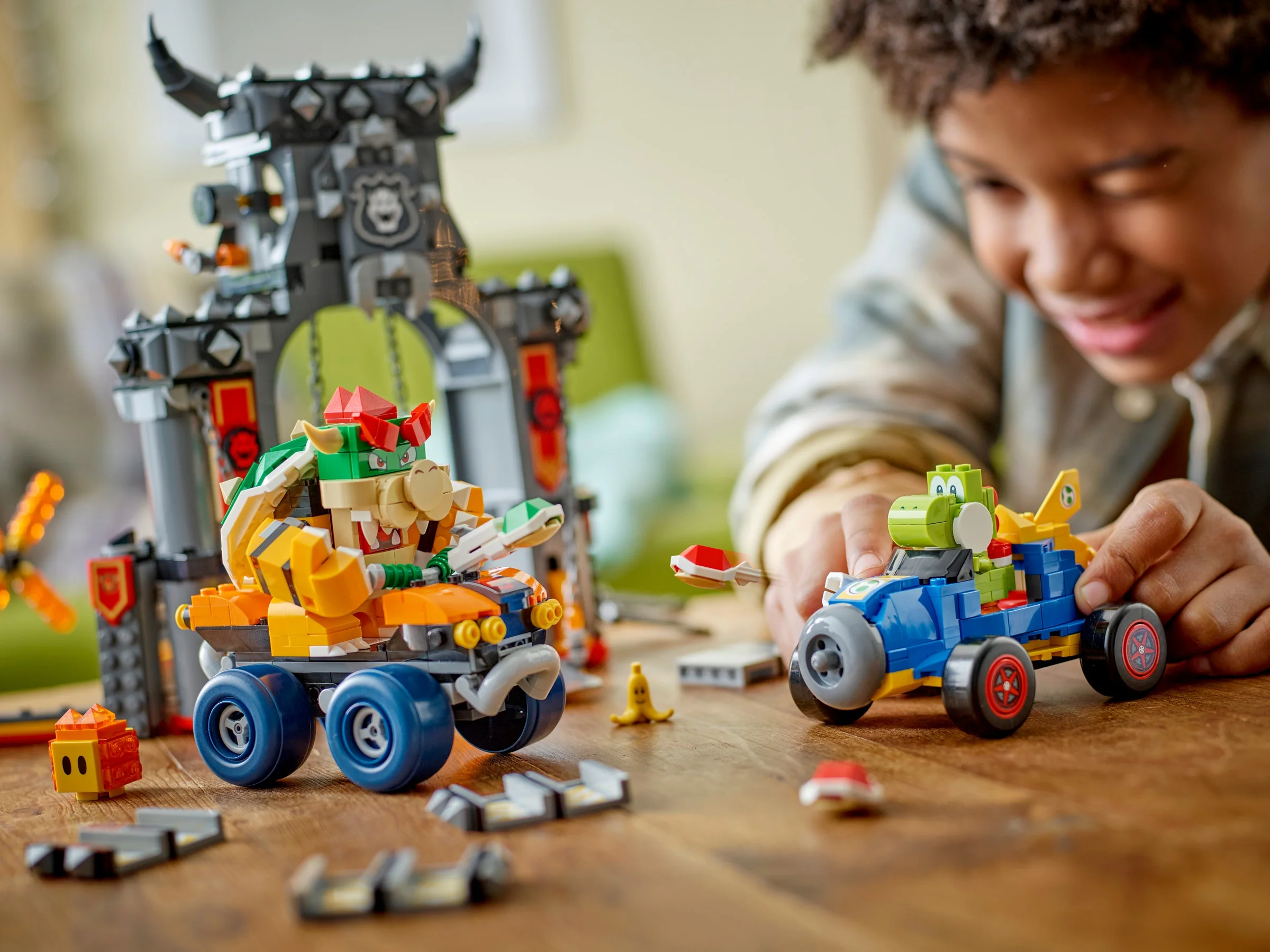 Copil se joacă cu setul LEGO Super Mario Castelul lui Bowser, mașinile sunt în prim-plan.