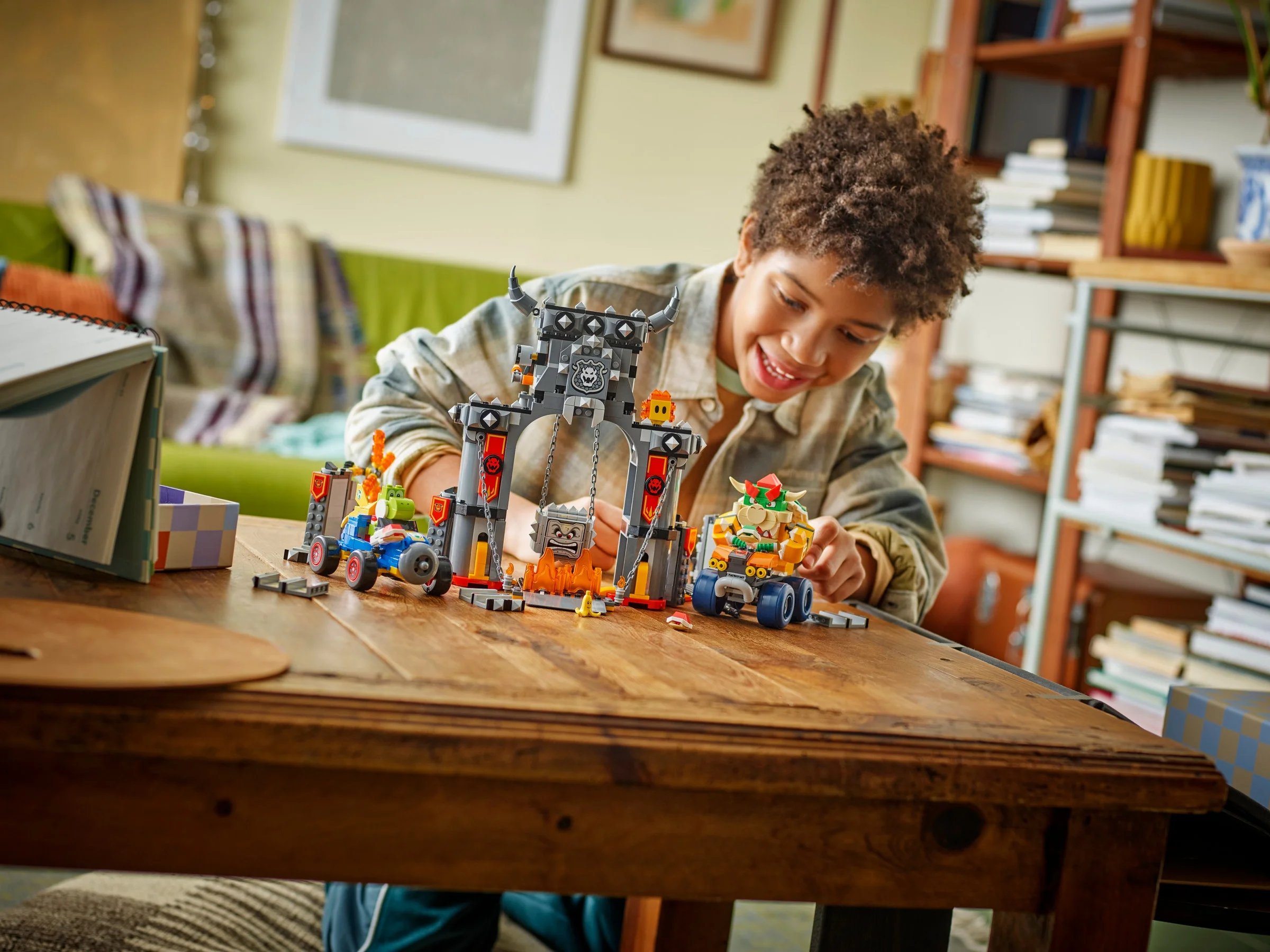 Imagine cu un copil jucându-se cu setul LEGO Bowser's Castle, arătând castelul și vehiculele incluse.