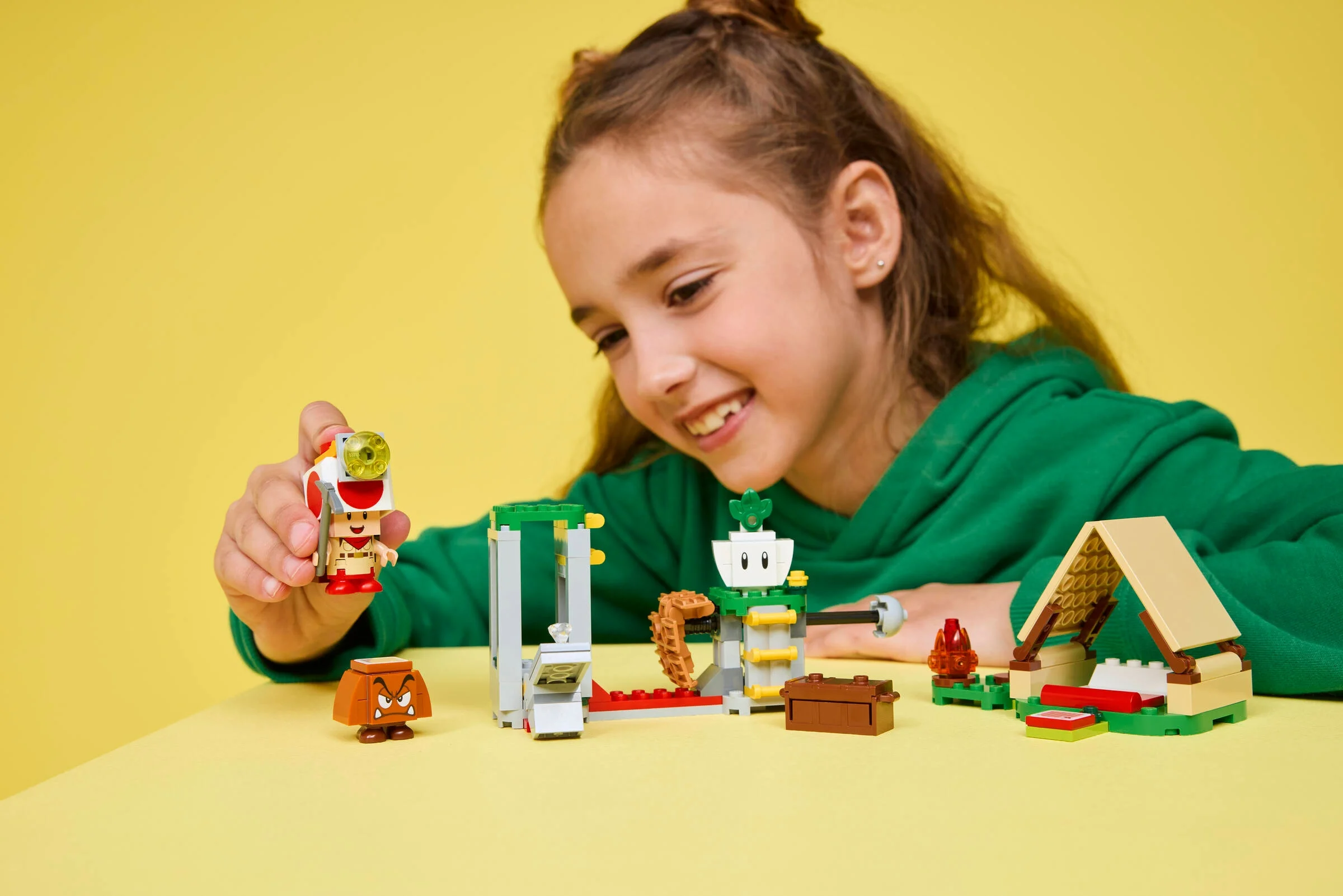 Fetiță zâmbitoare se joacă cu setul LEGO Captain Toad, explorând și construind.