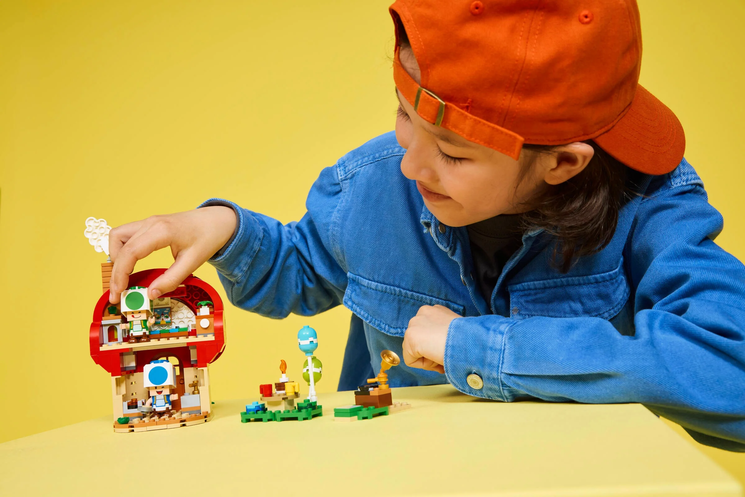 Copil construind setul LEGO Casa lui Toad. Atmosferă de joacă și creativitate.