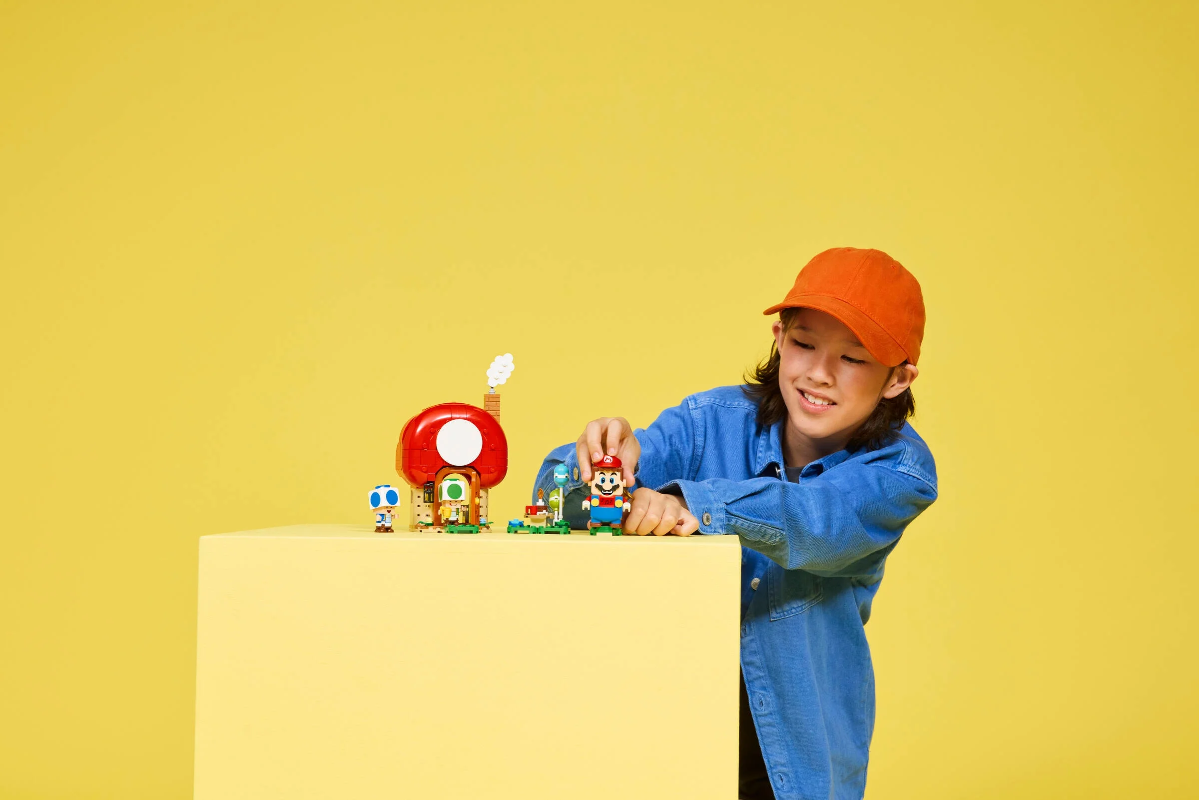 Copil interacționând cu setul LEGO Casa lui Toad. Atmosferă veselă și jucăușă.