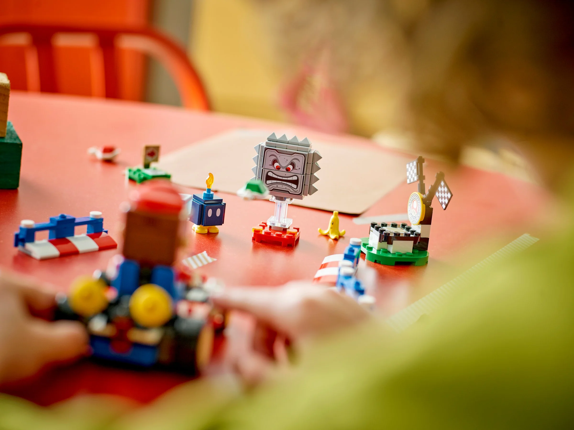 Copil interacționând cu setul LEGO Mario Kart, jucându-se cu diverse elemente ale setului.