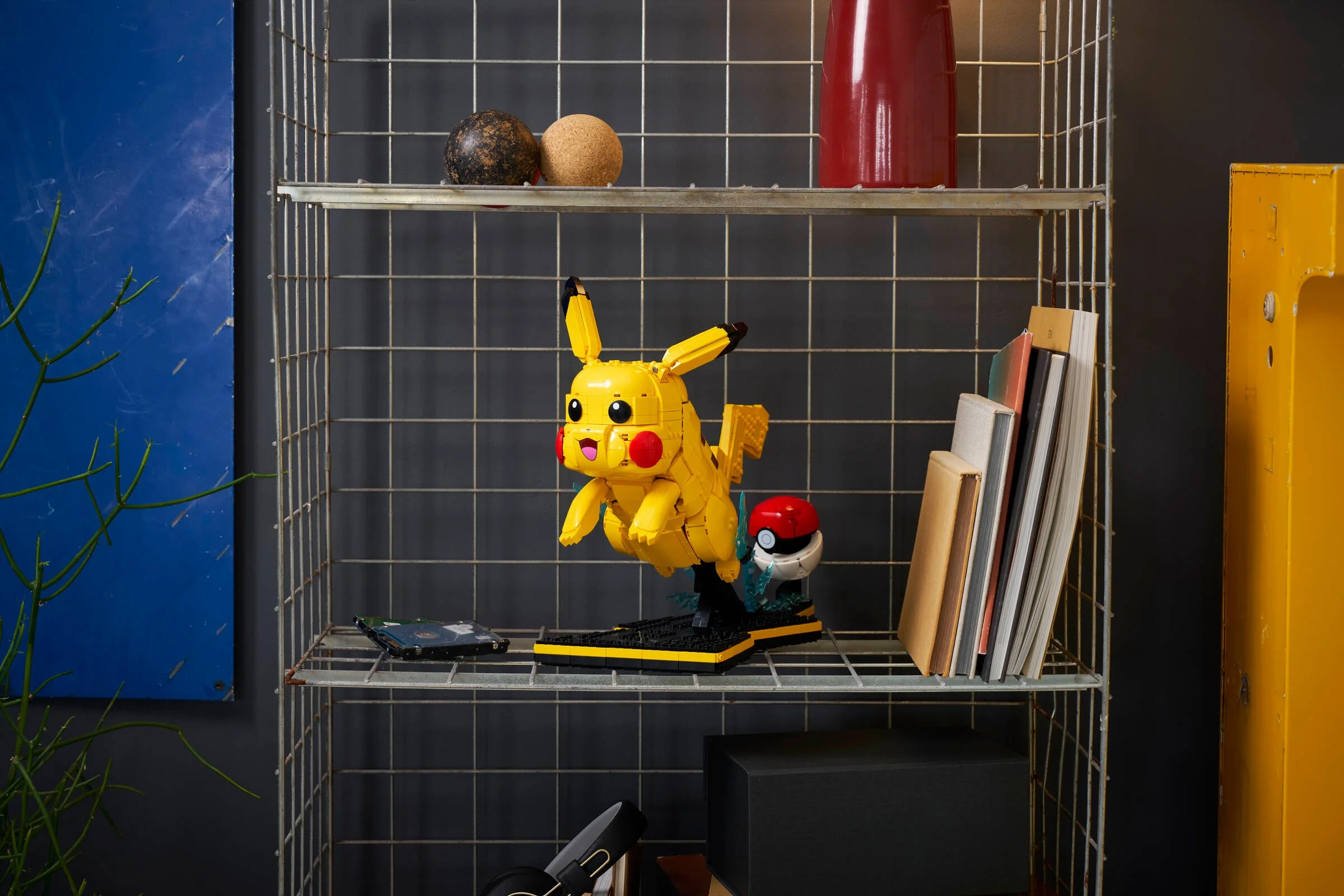 Pikachu și Poké Ball construite din LEGO, expuse pe un raft metalic. Detaliu al modelului.