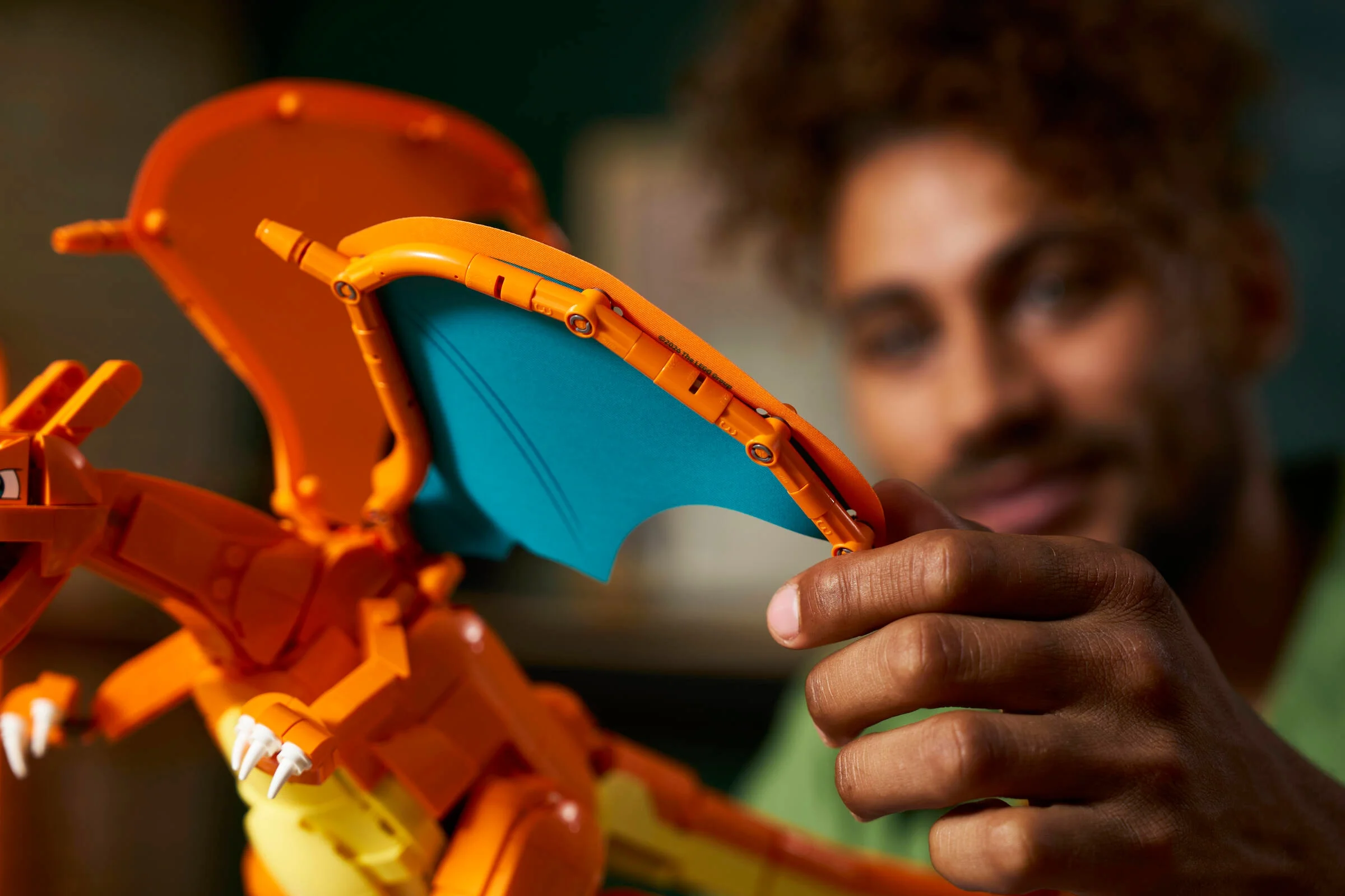Un bărbat construiește aripile lui Charizard LEGO. Detaliu apropiat al modelului.