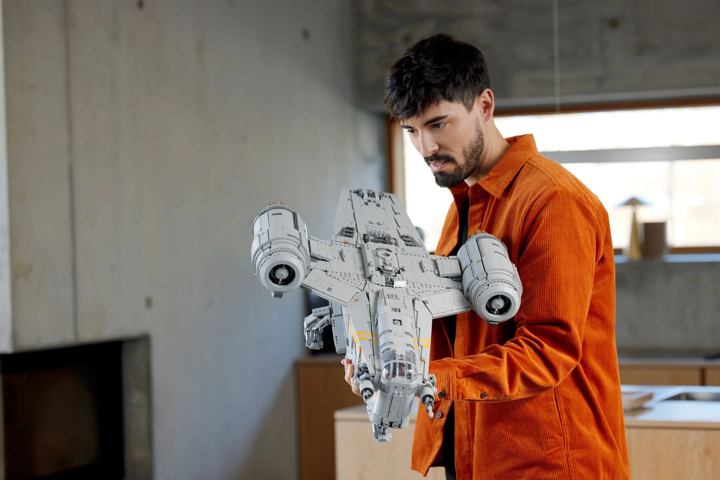 Un adult examinează cu atenție modelul Razor Crest, detaliind complexitatea construcției.