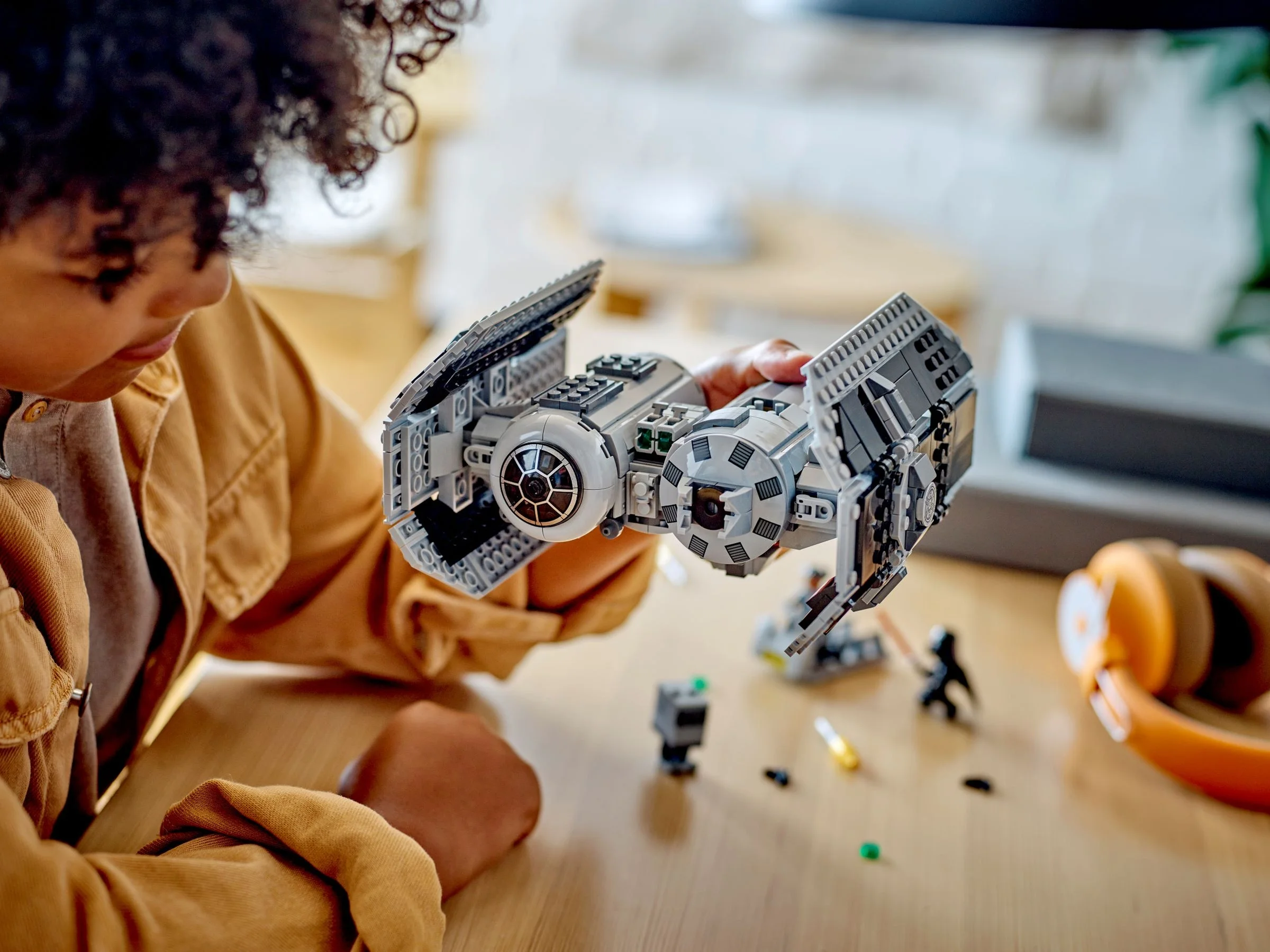 Un copil ține în mână un model LEGO TIE Bomber. Construcție detaliată și minifigurine incluse.