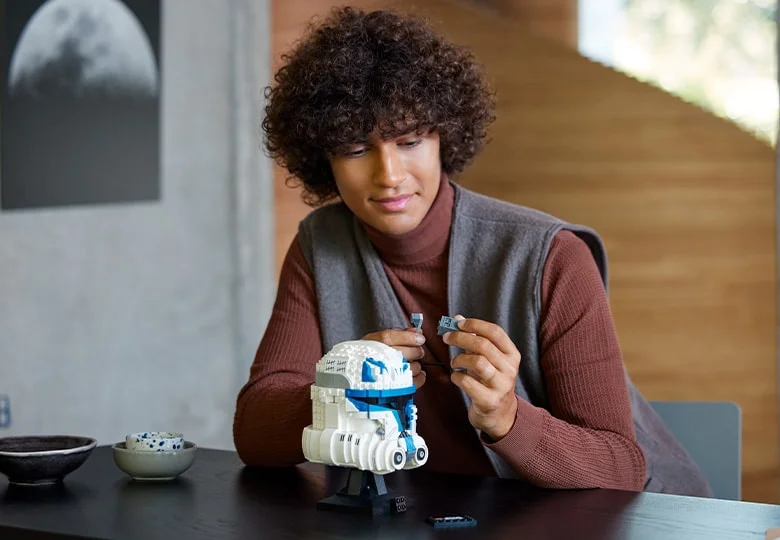 O persoană construiește casca LEGO Captain Rex. Detaliile sunt clare, luminozitatea e bună.