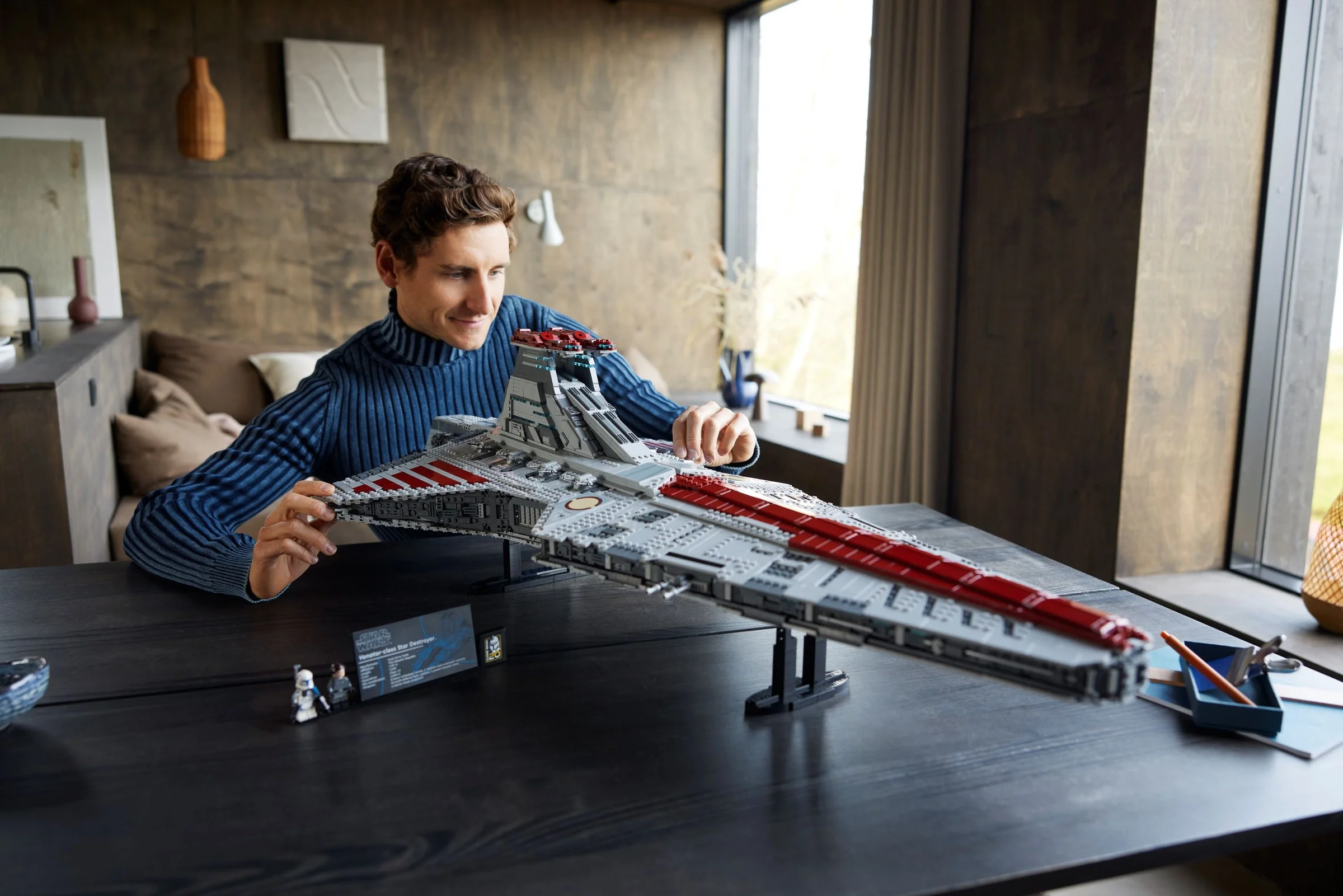 Un bărbat inspectează modelul LEGO al crucișătorului Venator, arătând detaliile complexe.