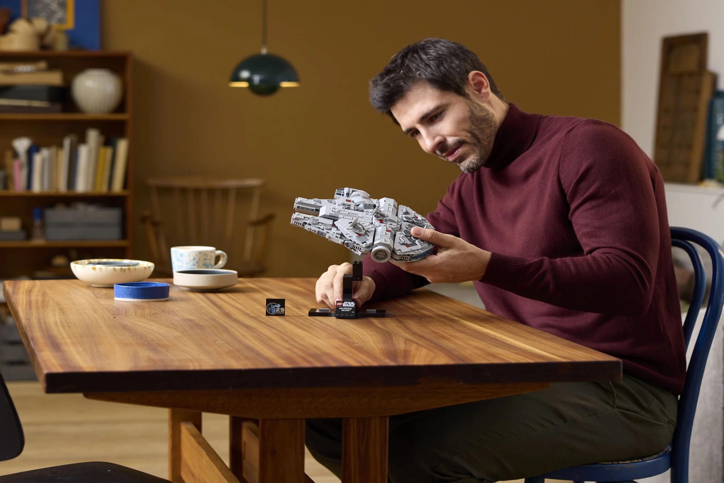 Bărbat admirând modelul Millennium Falcon LEGO Star Wars, pe suportul său.