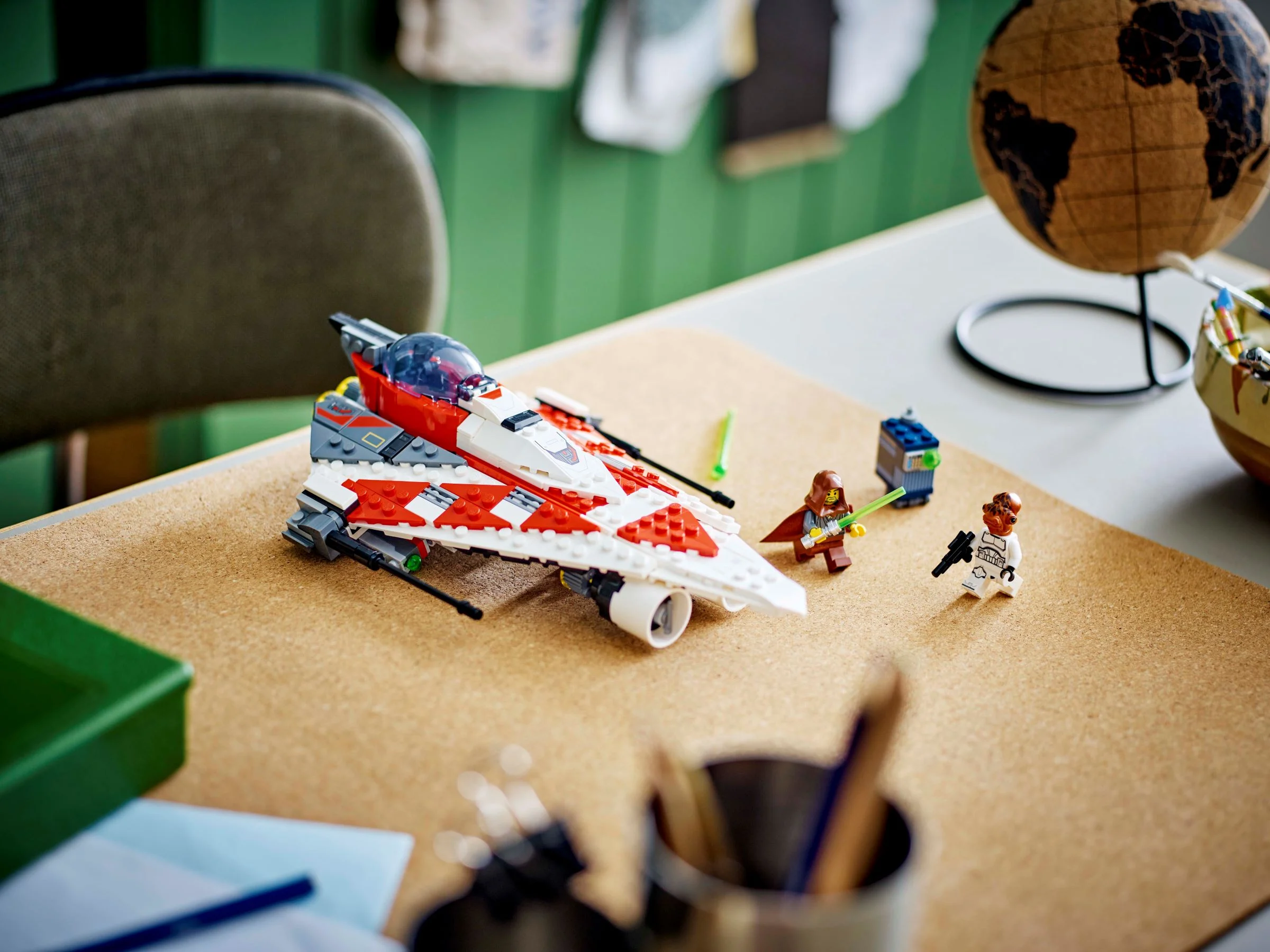 Avionul Jedi Bob și minifigurinele pe un birou. Atmosferă creativă, jucărie și glob pământesc.