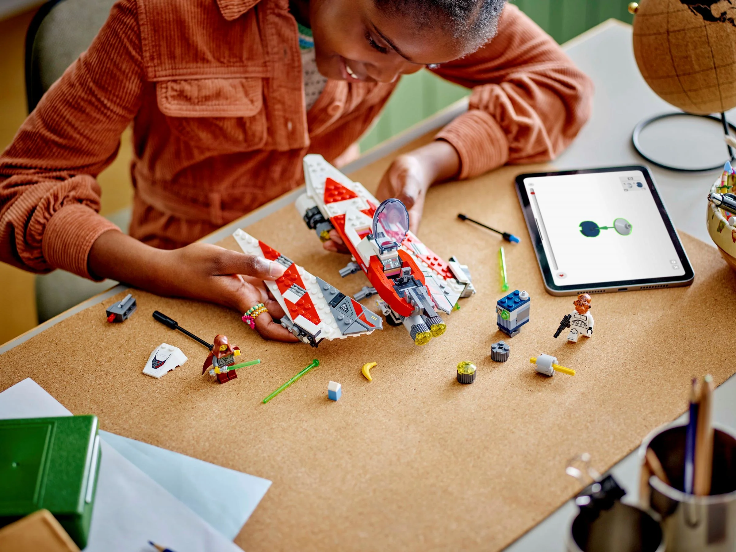 O tânără construiește Starfighter-ul Jedi Bob folosind instrucțiuni digitale pe tabletă.