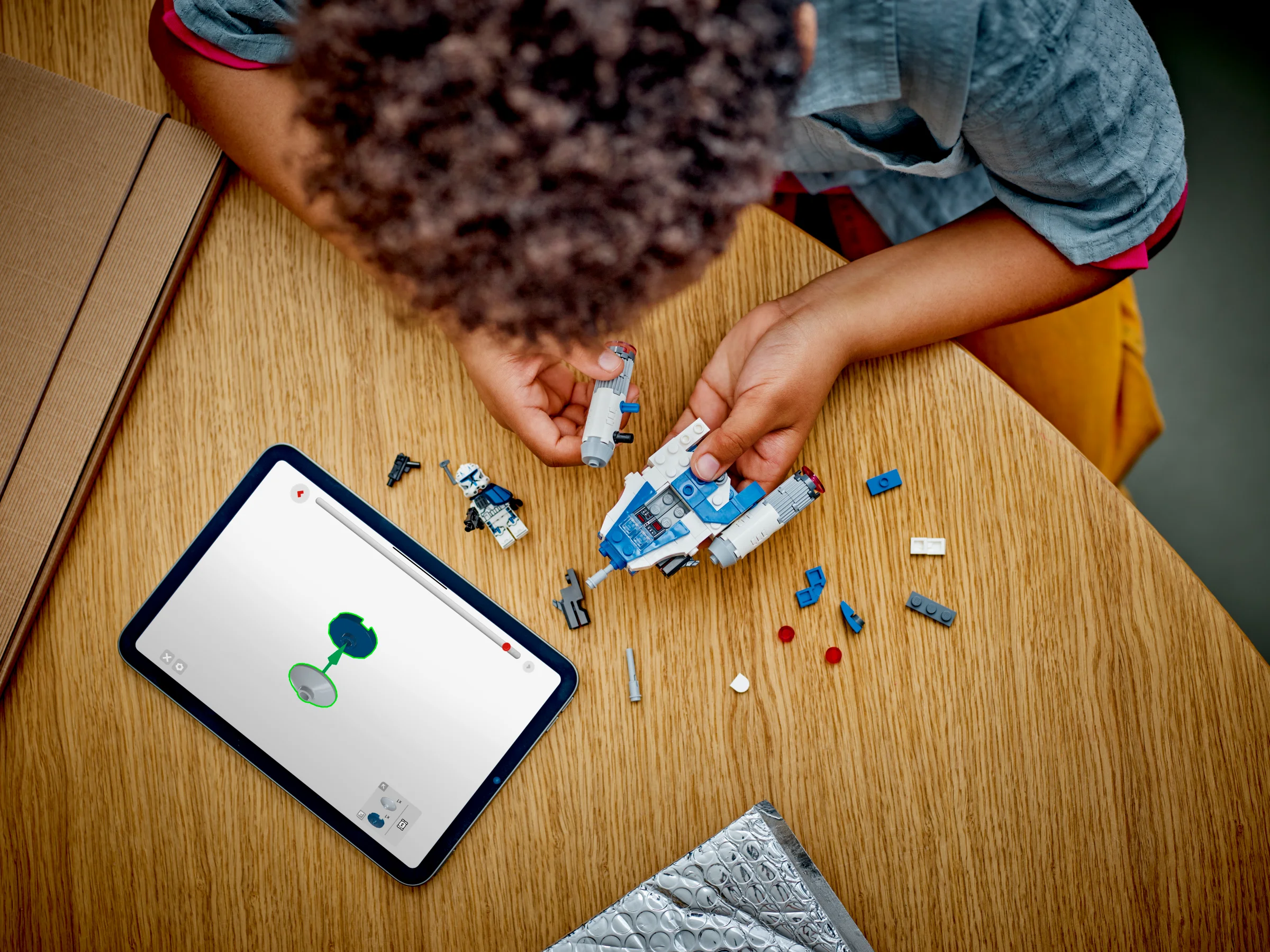 Copil asamblând setul LEGO Captain Rex Y-wing Microfighter folosind instrucțiuni digitale pe tabletă.